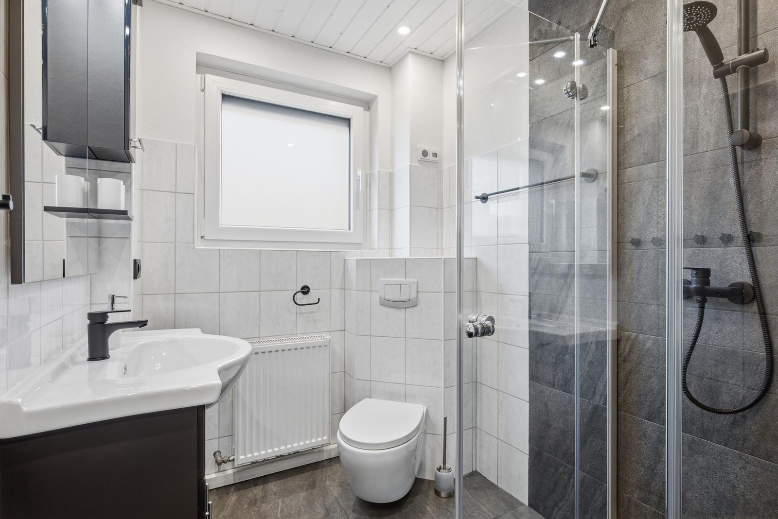 Badezimmer mit Dusche, Toilette und Waschbecken.