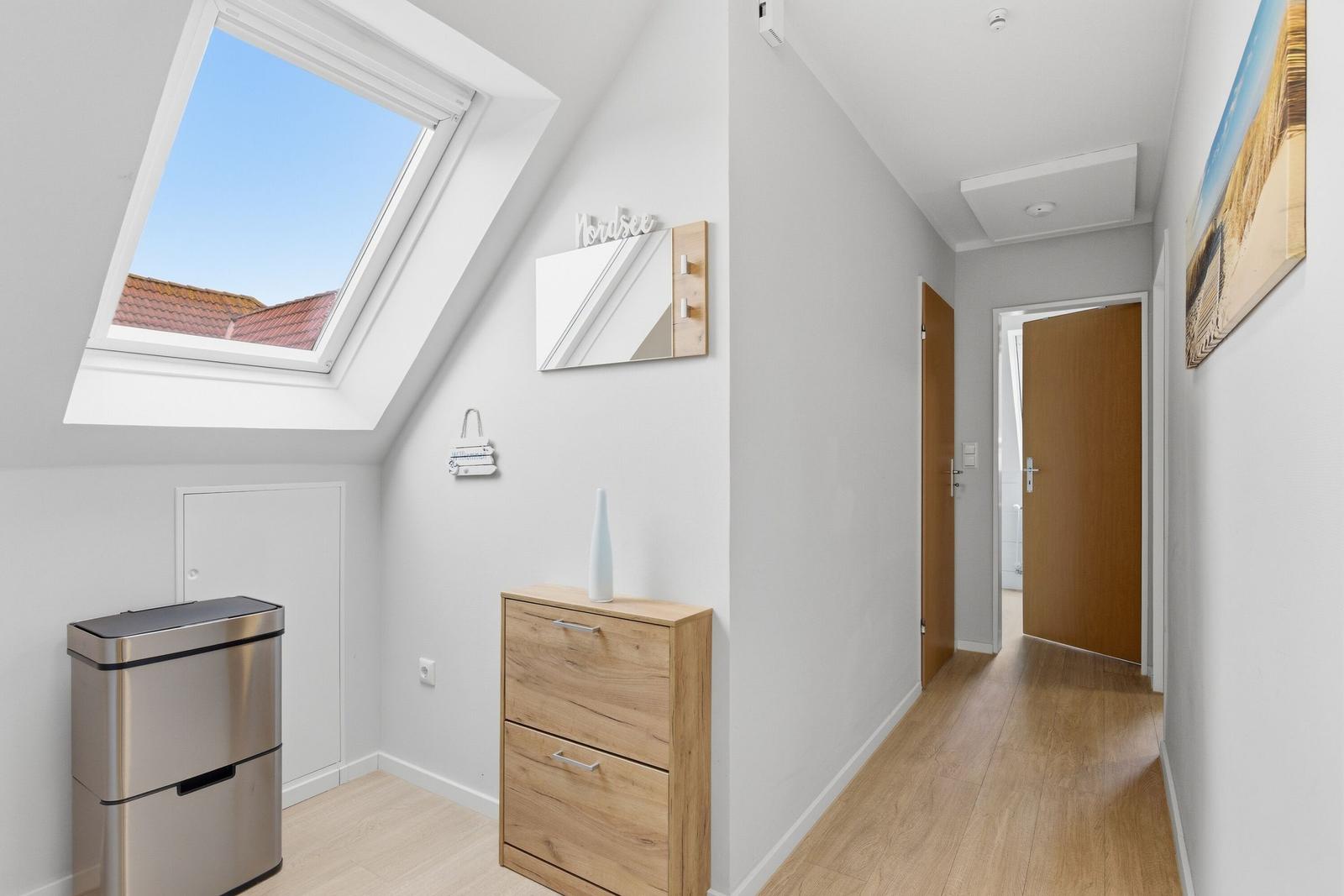 Flur mit Holzboden, Schrank und Dachfenster. Tür führt in das Bad.