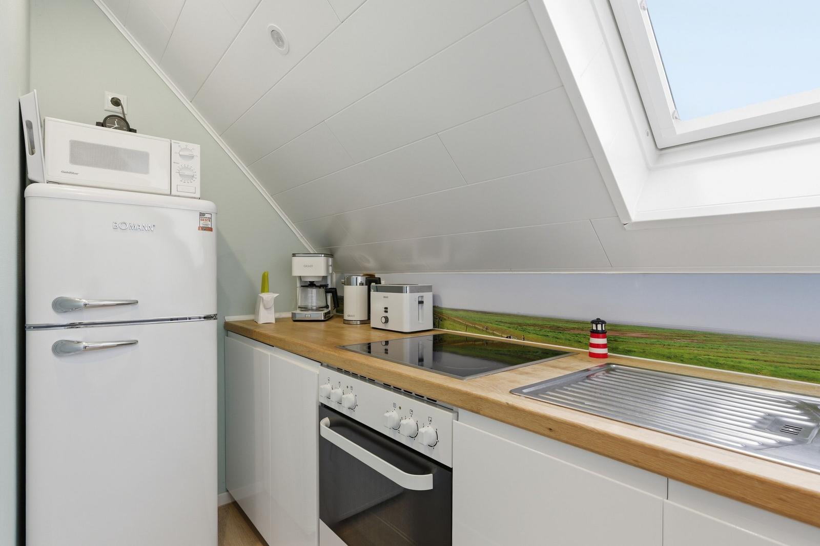 Küche mit Kühlschrank, Herd und Dunstabzugshaube unter Dachschrägen