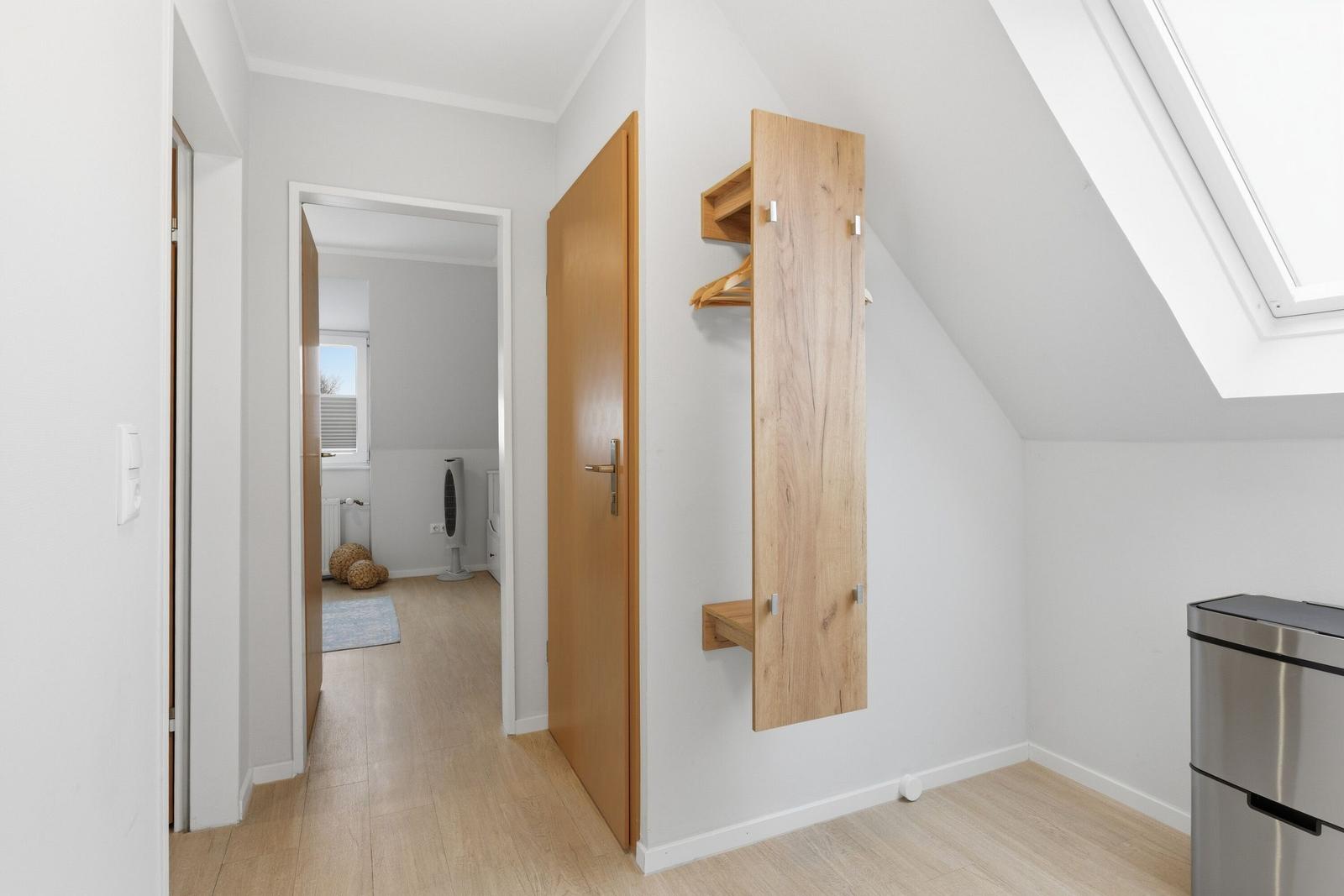 Dachgeschosszimmer mit Holzwandgarderobe und Dachfenster. Durchgang in benachbarte Räume.