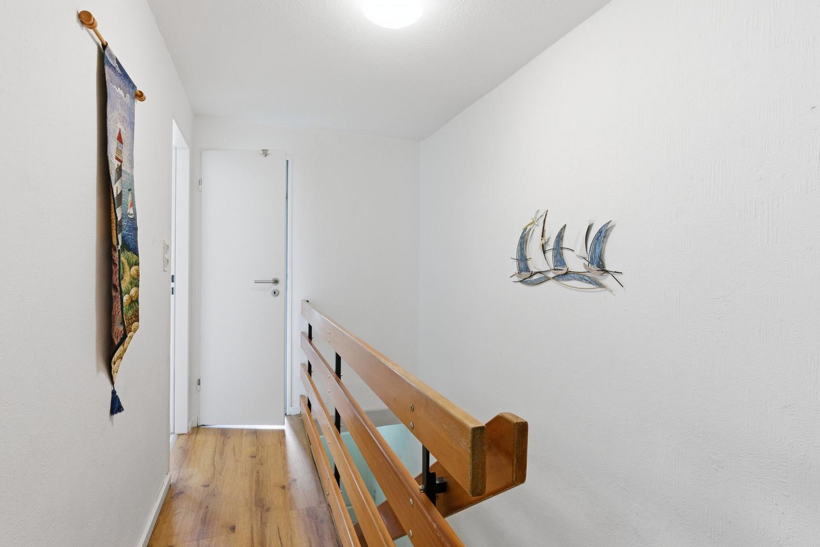 Flur mit Holzgeländer, Wandbildern und Tür