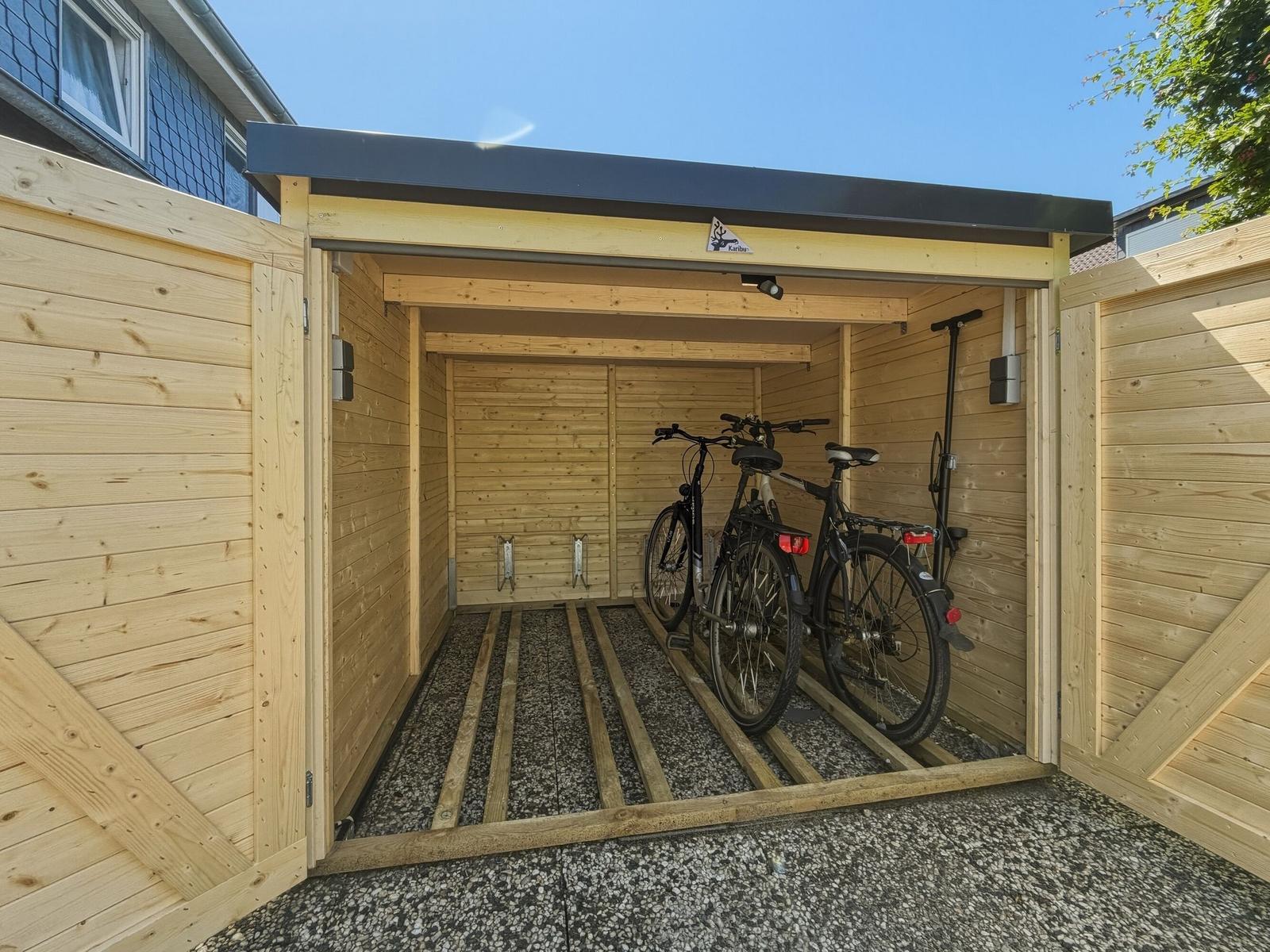 Holzgarage mit zwei Fahrrädern und Dachüberstand