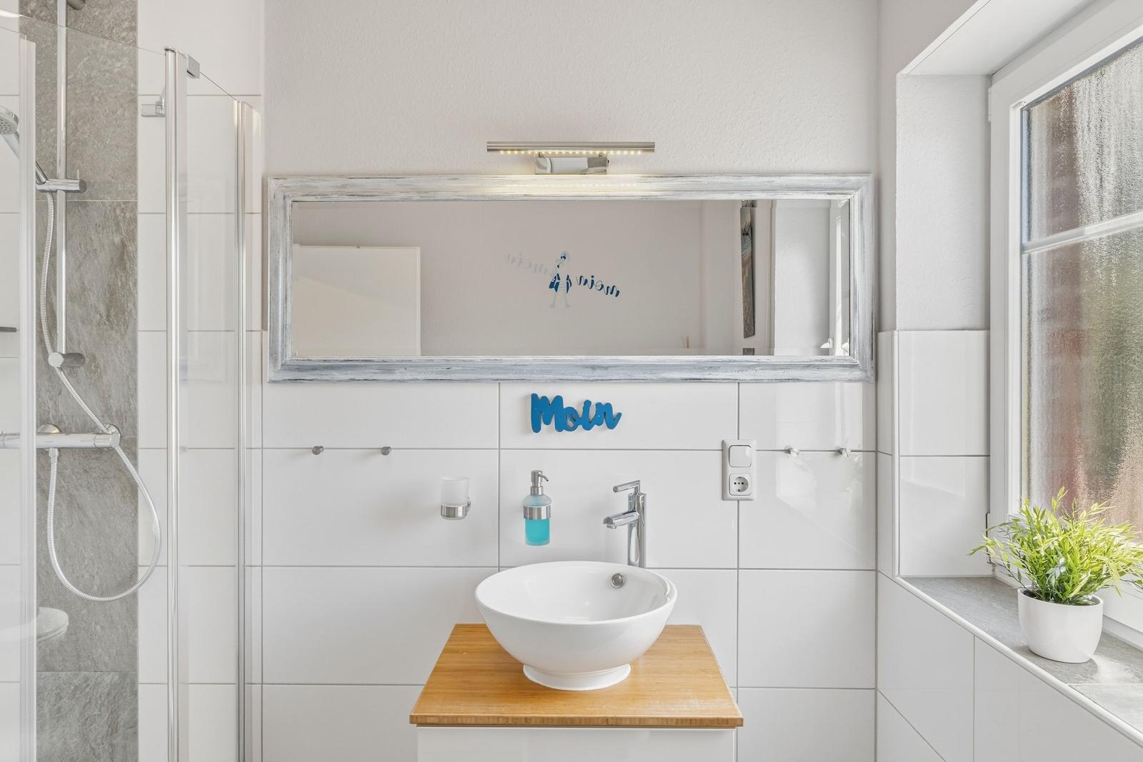 Badezimmer mit Dusche, Waschbecken und Fenster