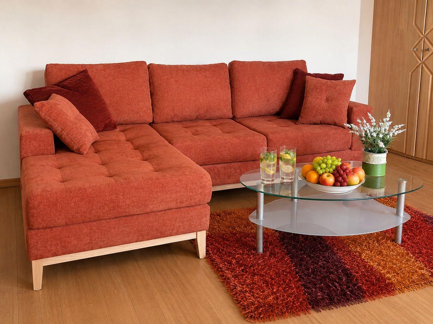 An L-shaped sofa with cushions is positioned in front of a table with fruit and drinks.
