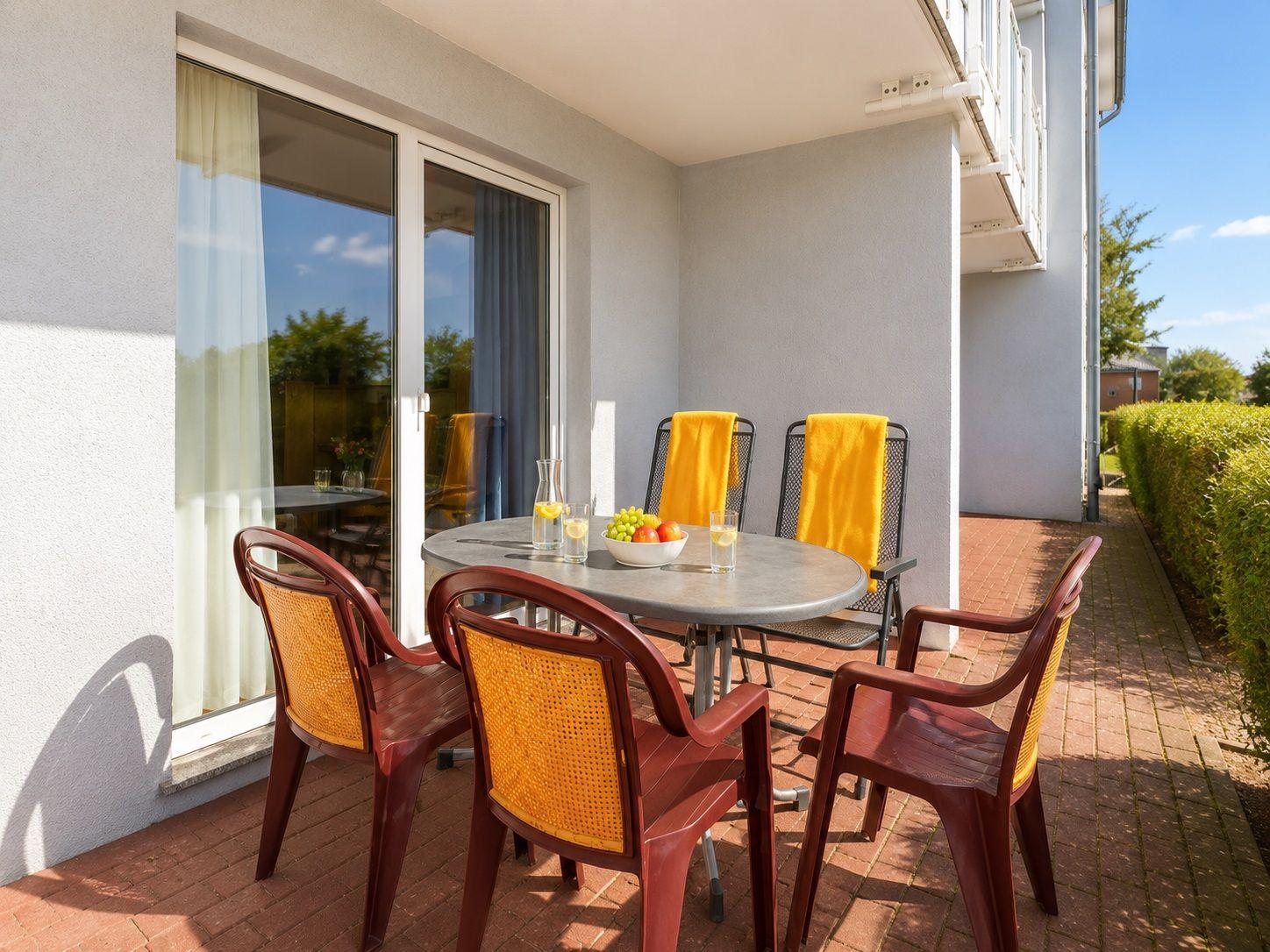 Terrace with round table and chairs, fruit bowl and yellow towels.