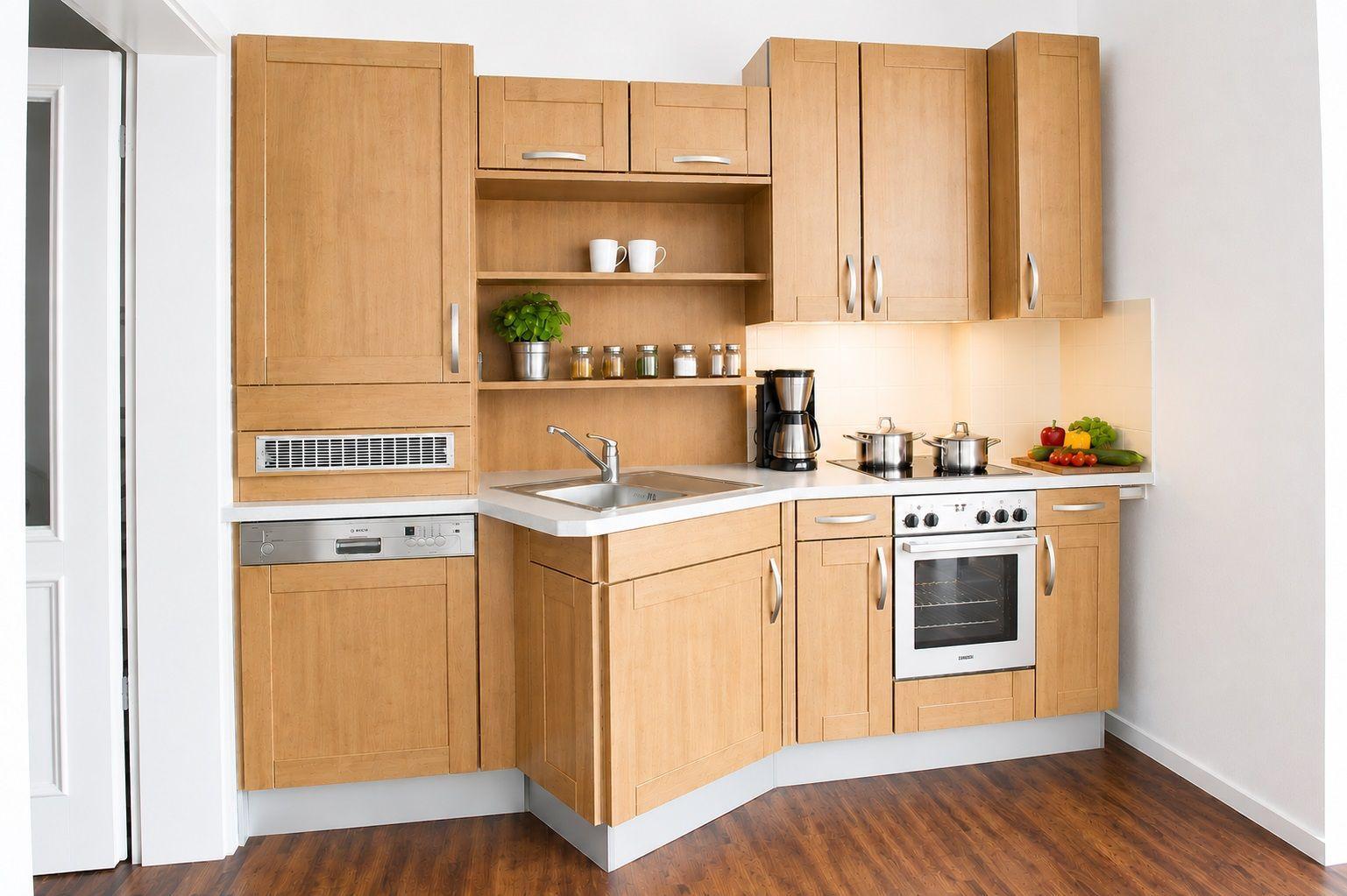 Küche mit Holzschränken, Spüle, Herd und Backofen sowie Obst und Gemüse auf der Arbeitsplatte.