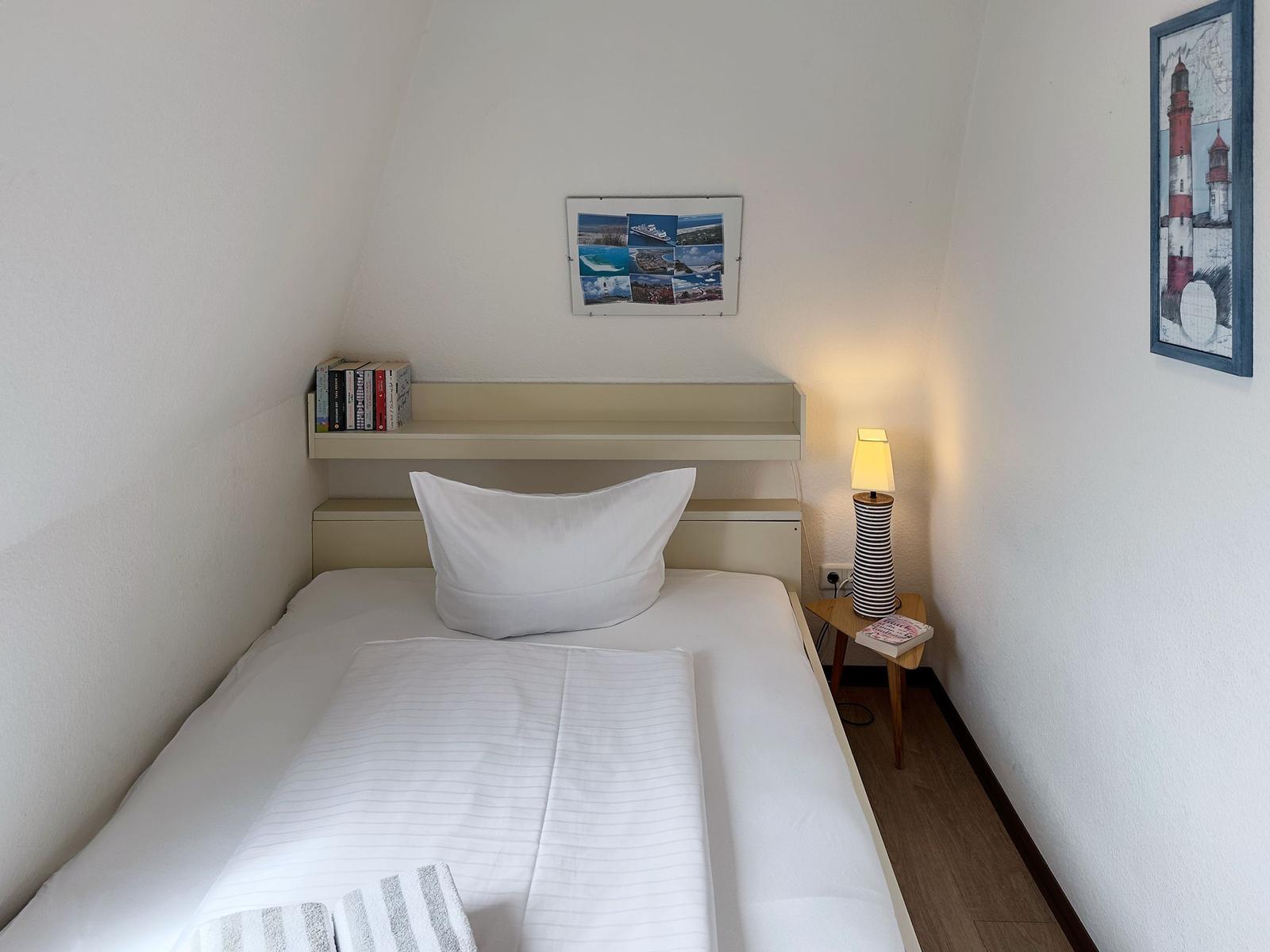 Ein Schlafzimmer mit einem Bett, einer Lampe und Wandbildern.