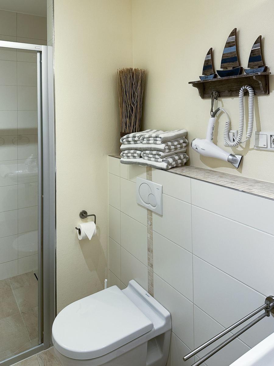 Bad mit Toilette, Dusche und Handtuchhalter mit Segelboot-Dekoration.