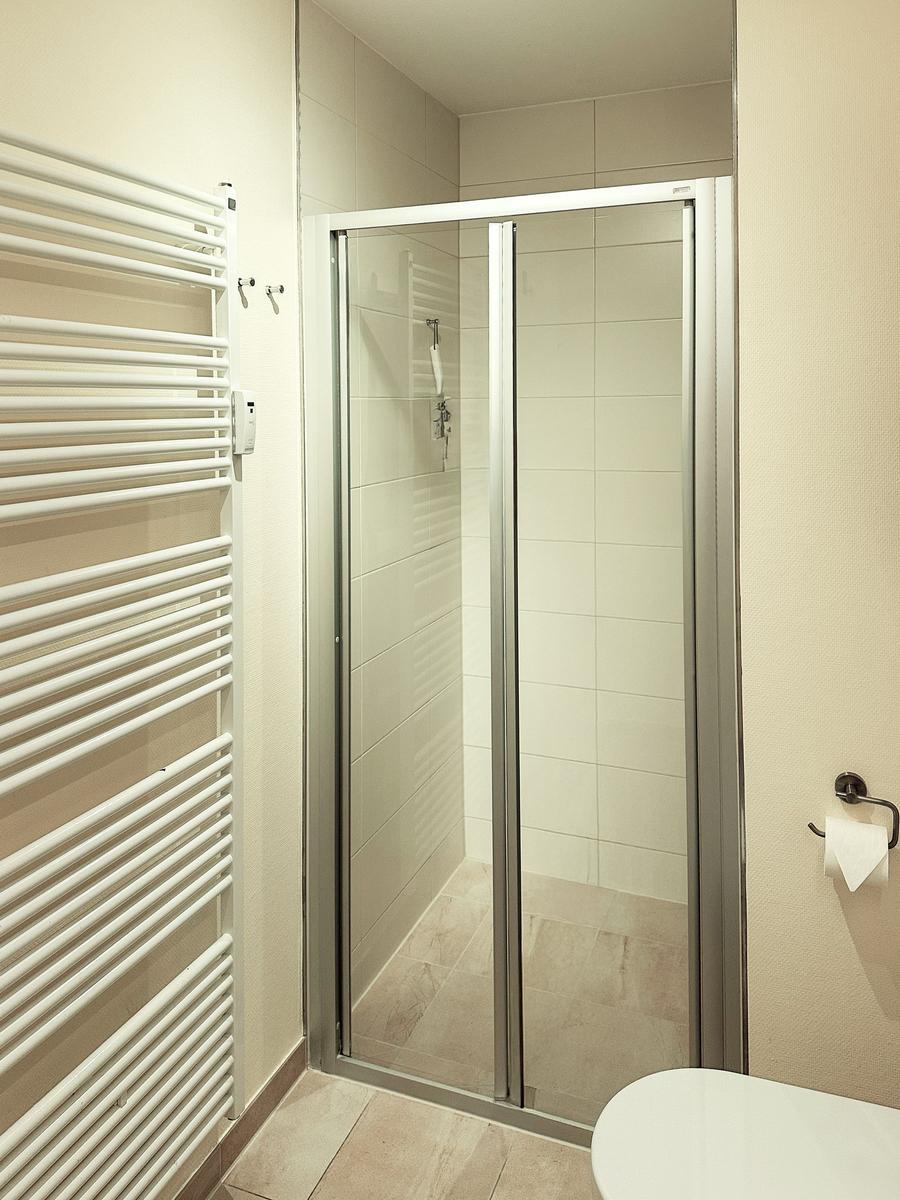 Dusche mit Glaswand, Heizkörper und Toilette in Badezimmer