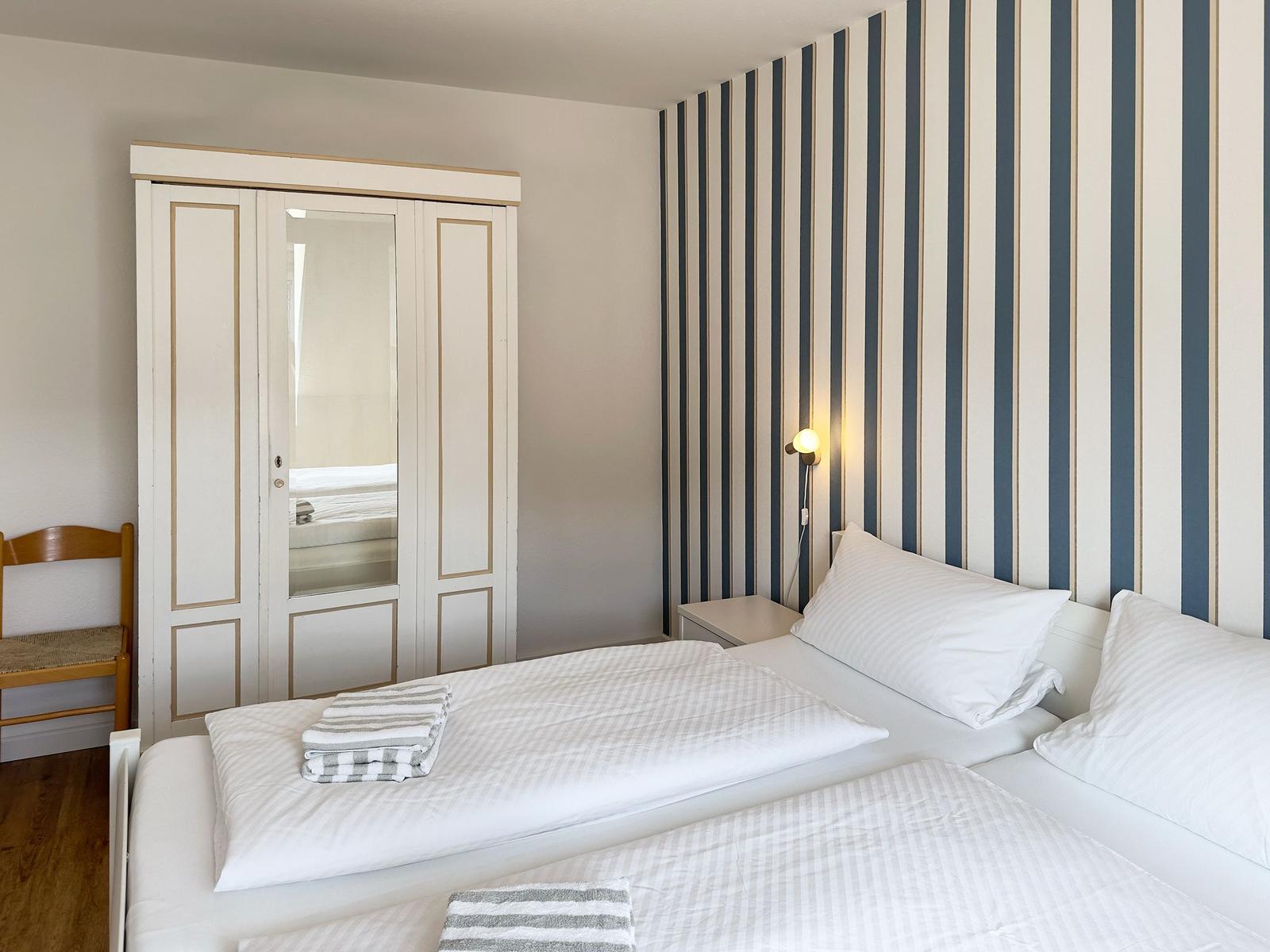 Bedroom with bed, wardrobe, and striped wall