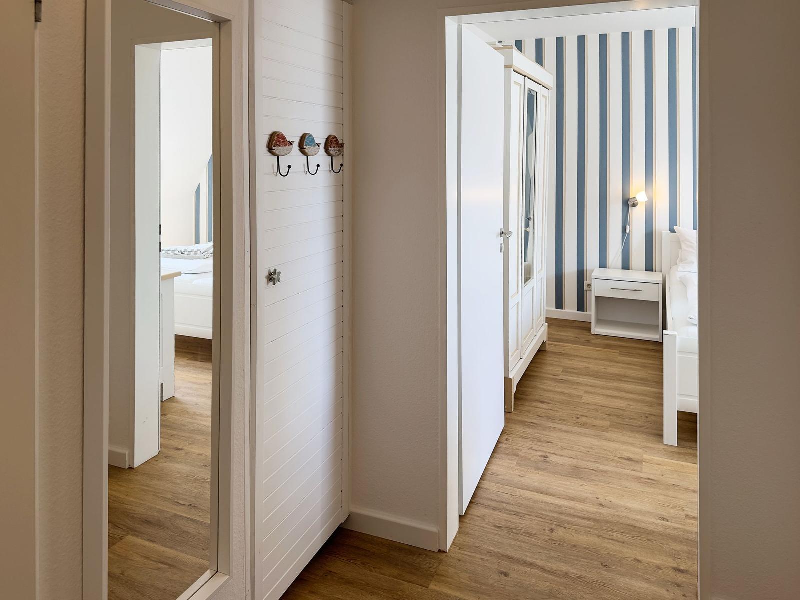 Hallway with view into bedroom and wardrobe with striped wall