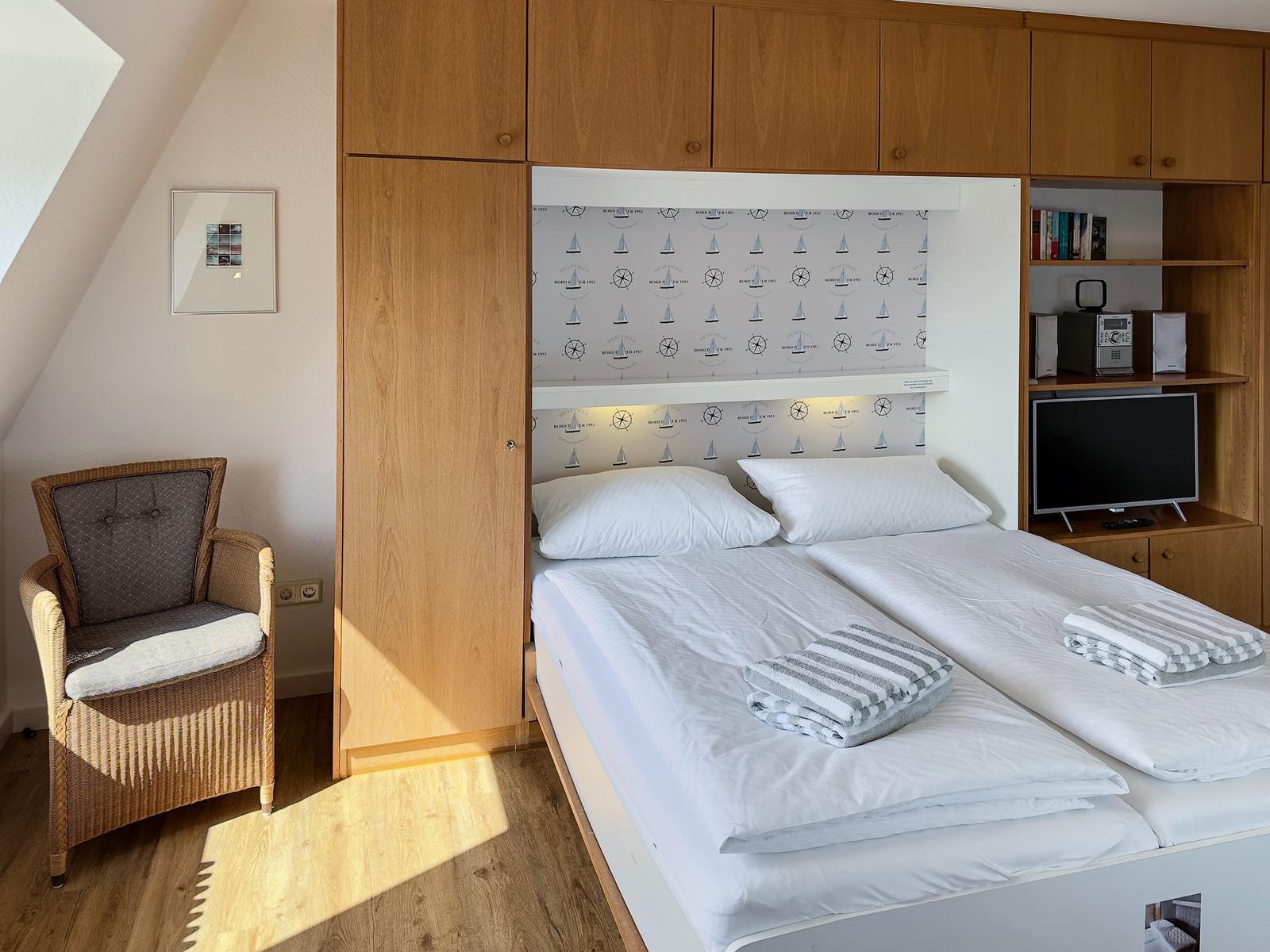 Room with double bed, wooden furniture, and TV. A picture hangs on the wall.
