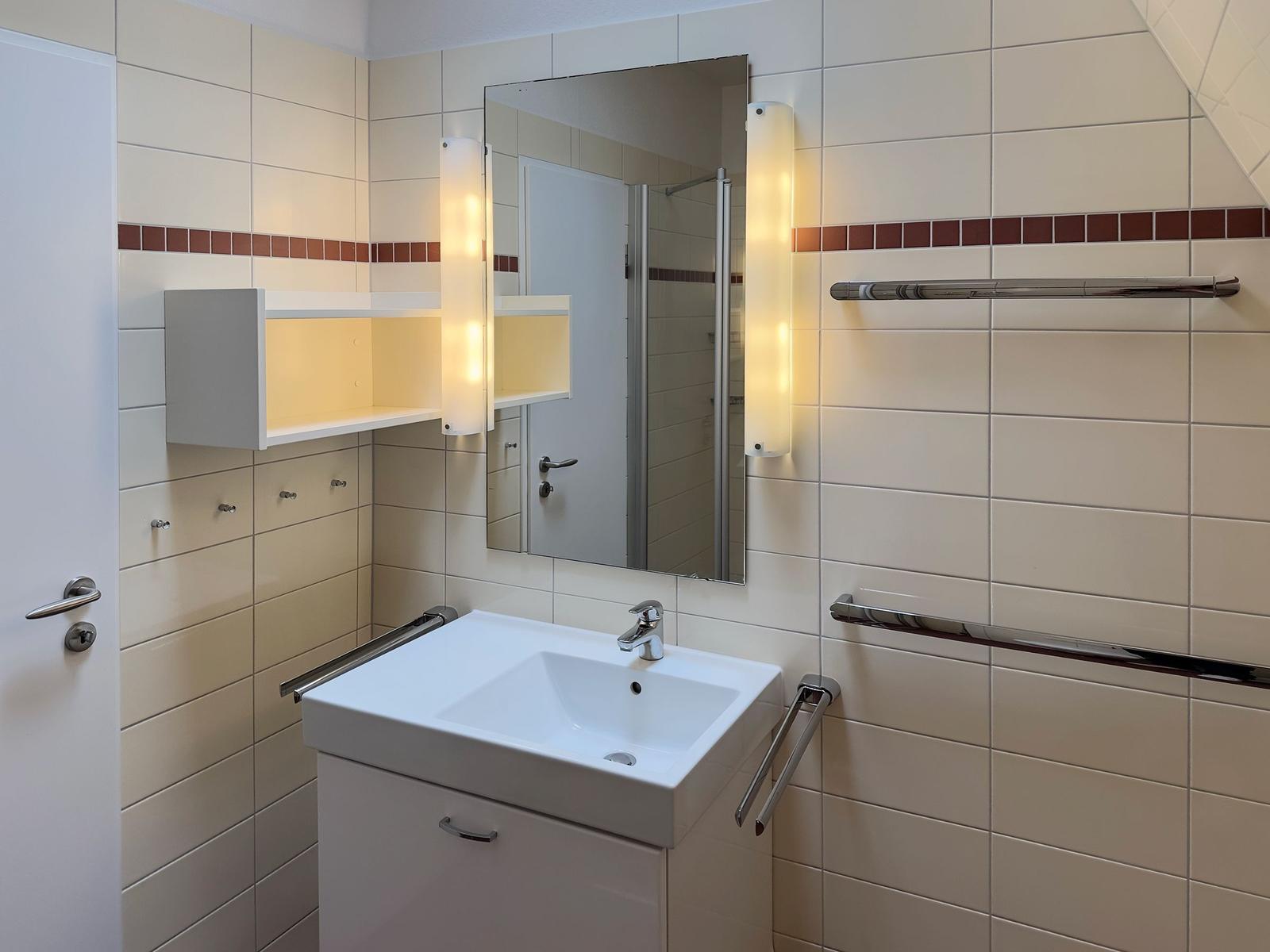 Bathroom with sink, mirror, and shower area.