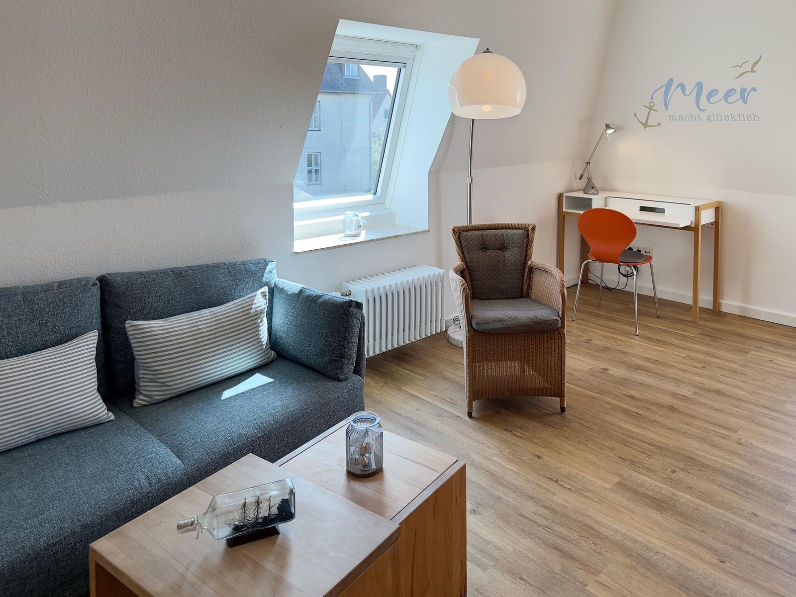 Living room with sofa, desk and skylight. Wooden floor and wall decor.