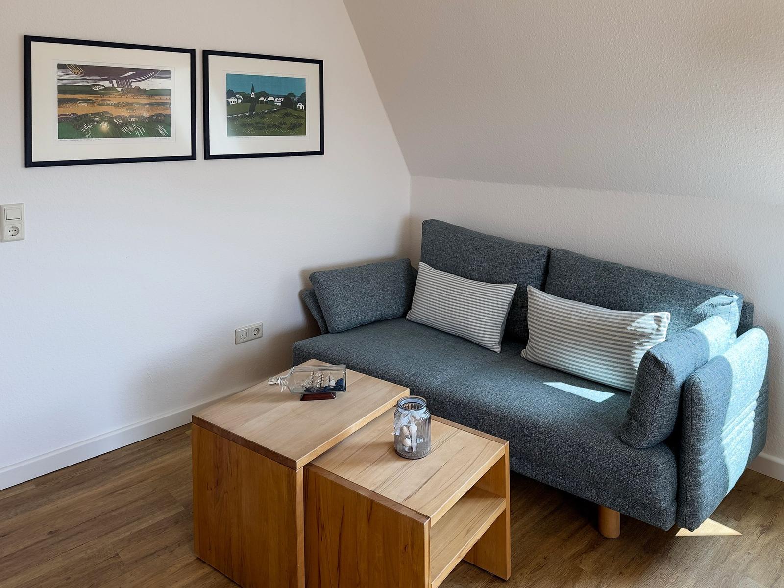A gray sofa with cushions and wooden table under sloped walls.
