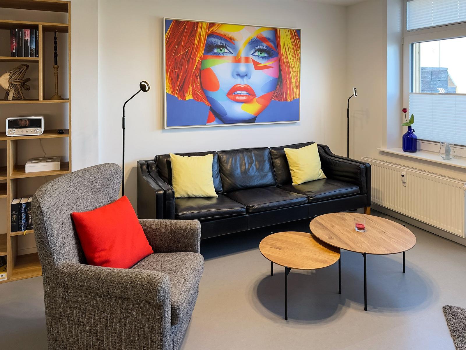 Black sofa with yellow cushions, gray armchair with red cushion, and wooden coffee table.