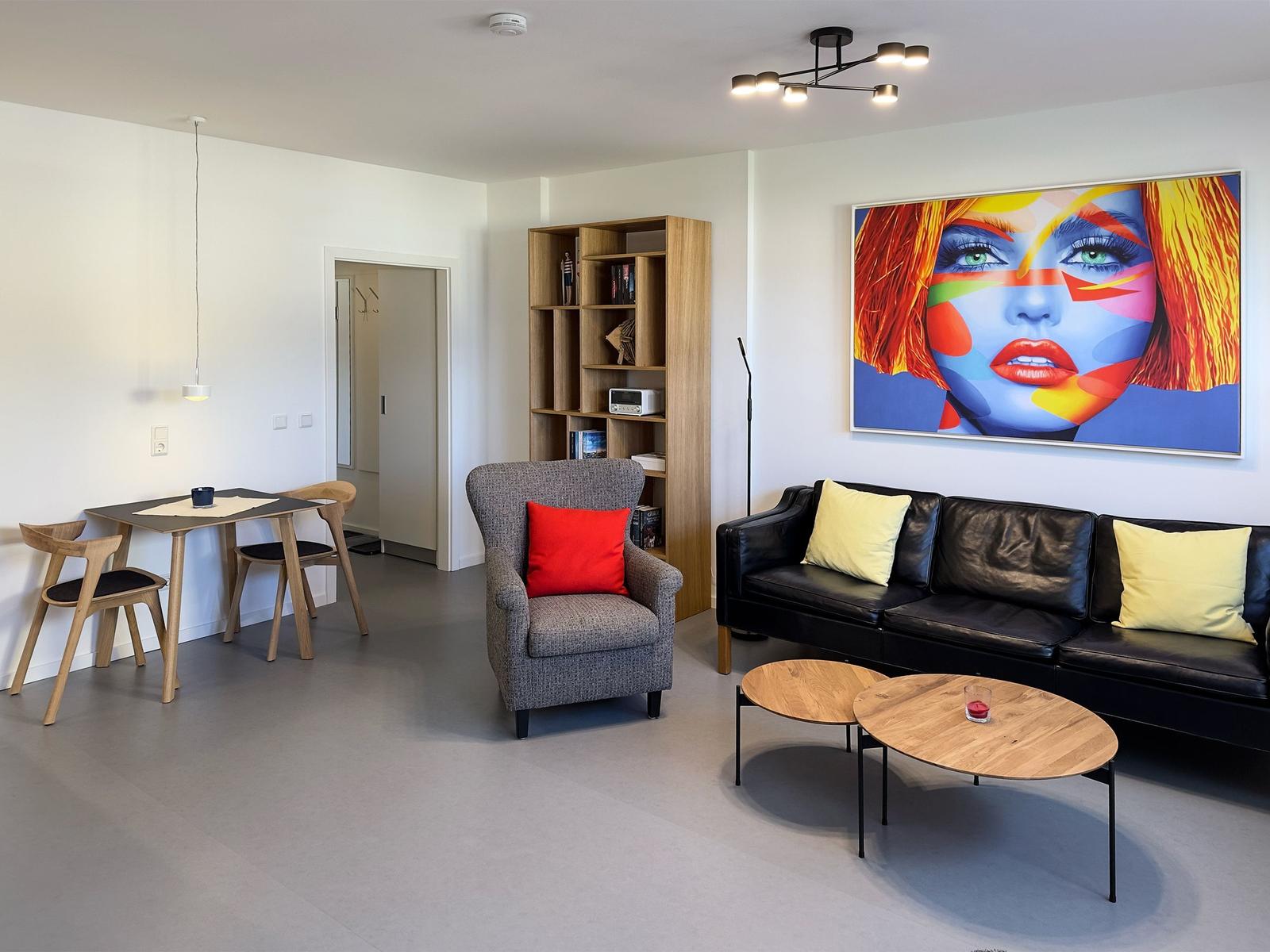 Living room with sofa, armchair, table, and wall art.