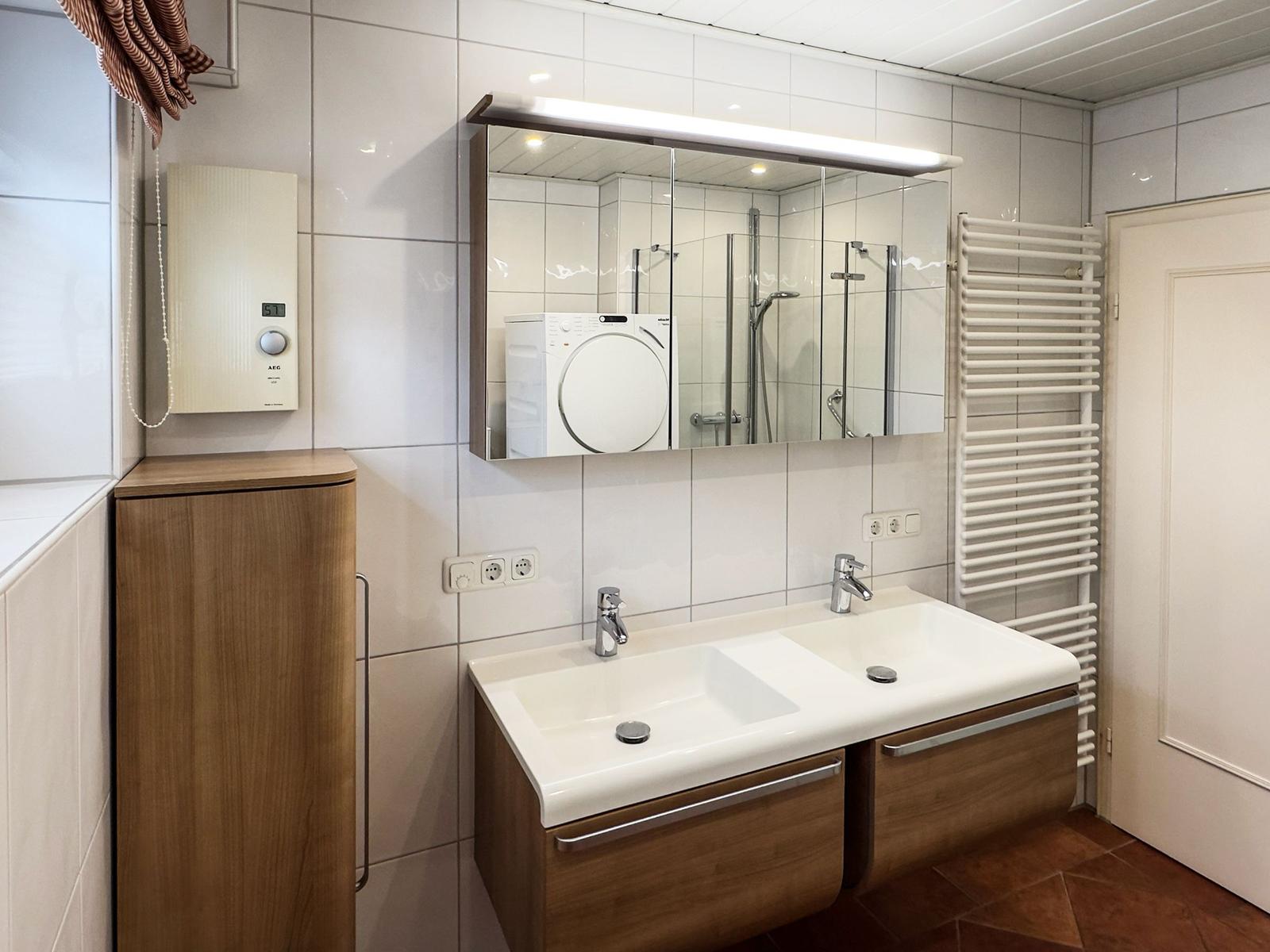 Badezimmer mit Doppelwaschbecken, Spiegelschrank und Heizkörper