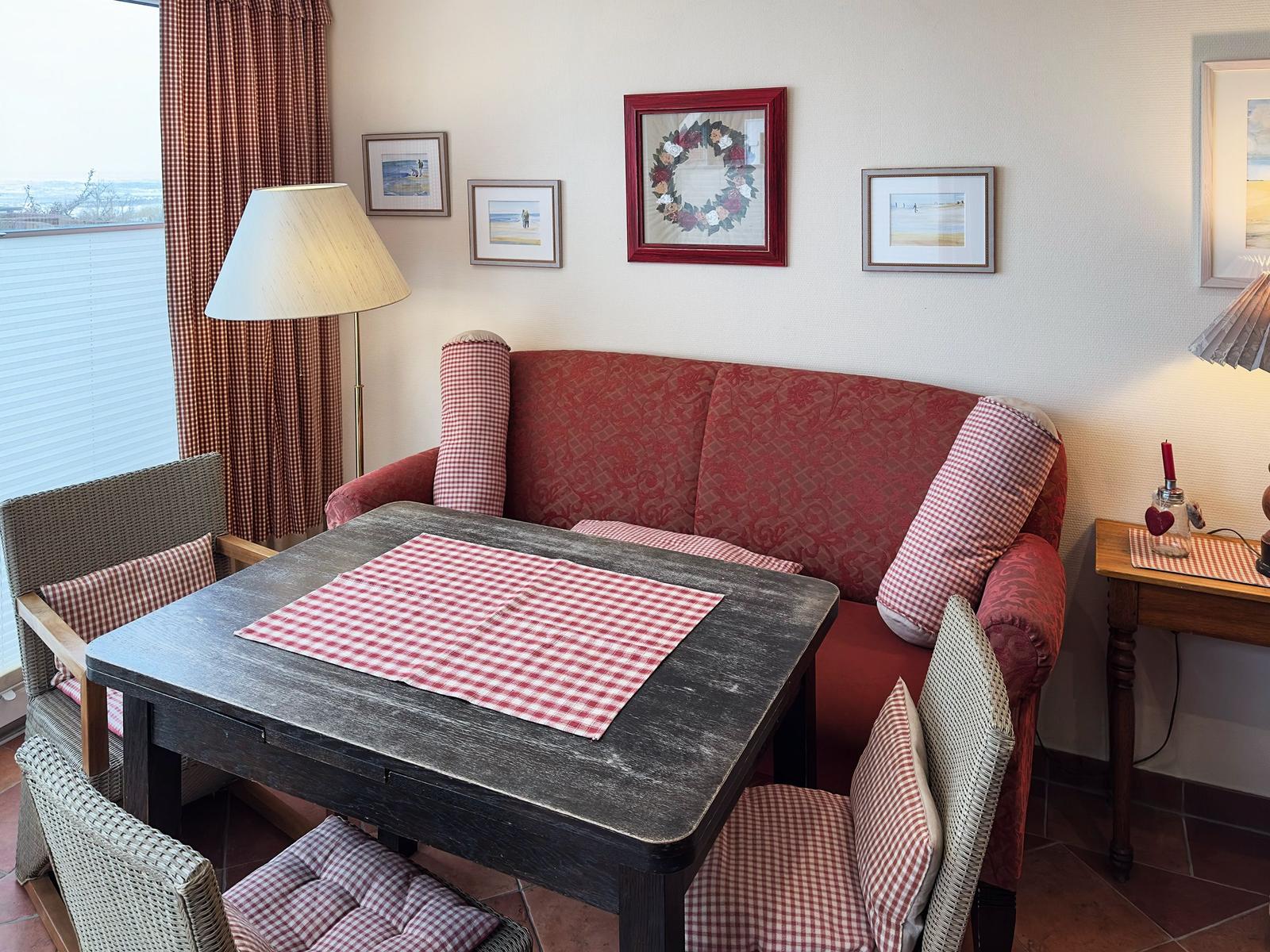 Ein Essbereich mit einem Tisch und Stühlen, einem Sofa und Bildern an der Wand.