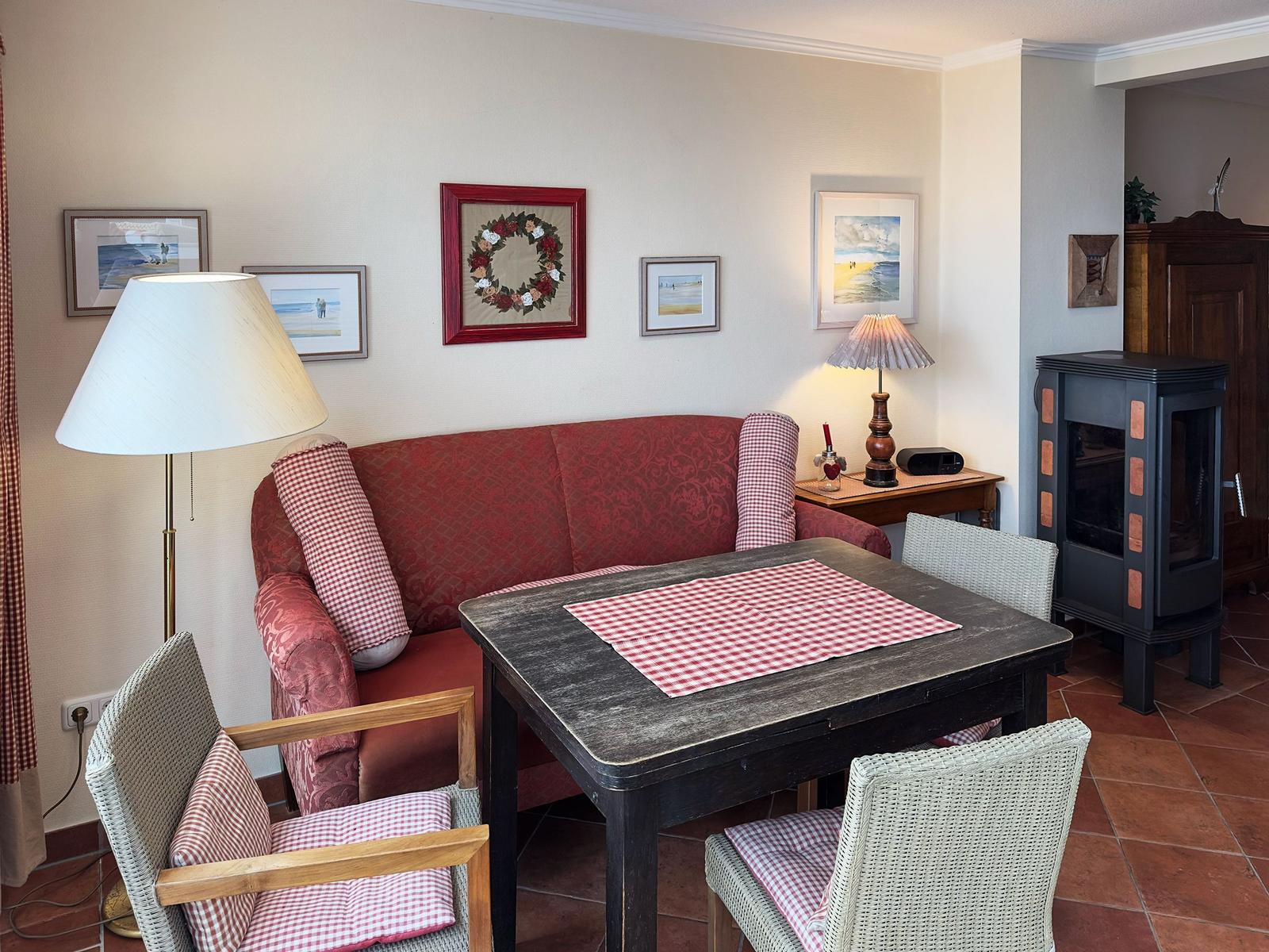 Ein Essbereich mit Tisch, Stühlen und Sofa. Wandbilder und Stehlampe sind sichtbar.