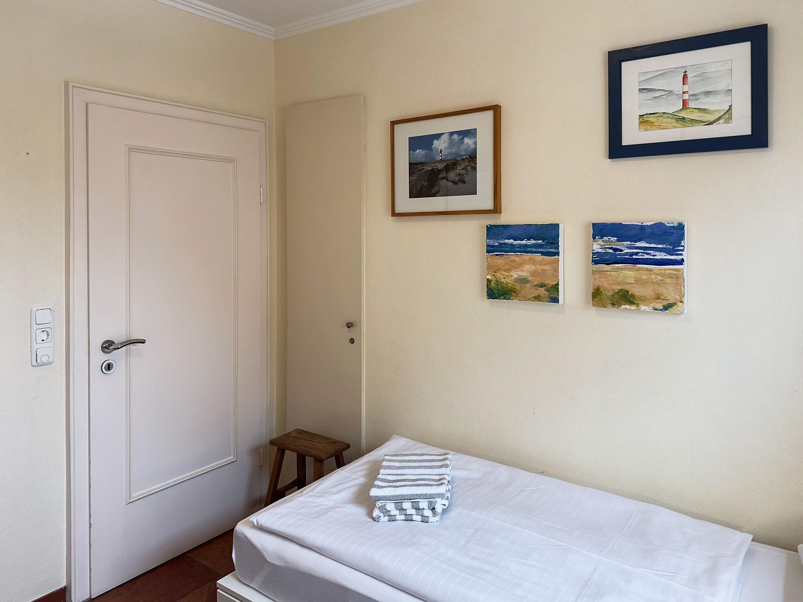 Schlafzimmer mit Bett, Tür und Wandbildern an der Wand.