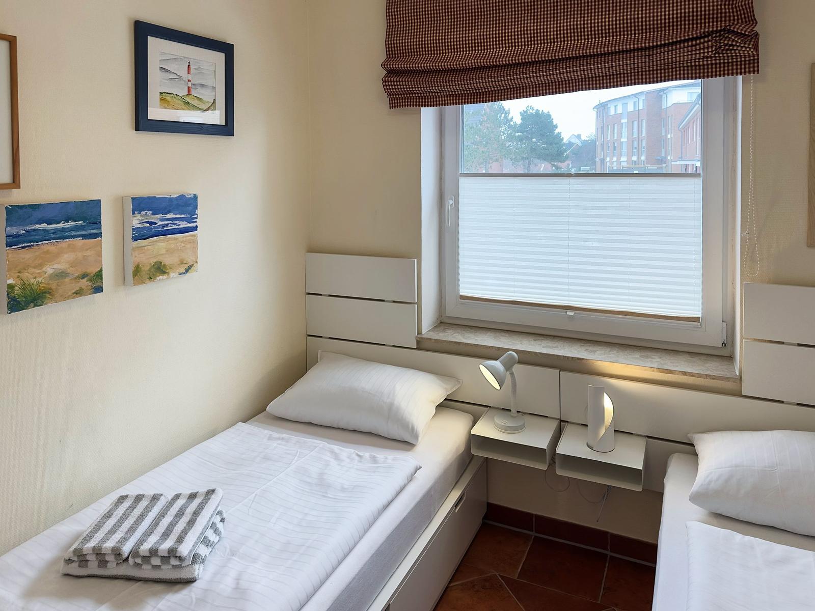 Zimmer mit zwei Betten, Fenster und Wandbildern