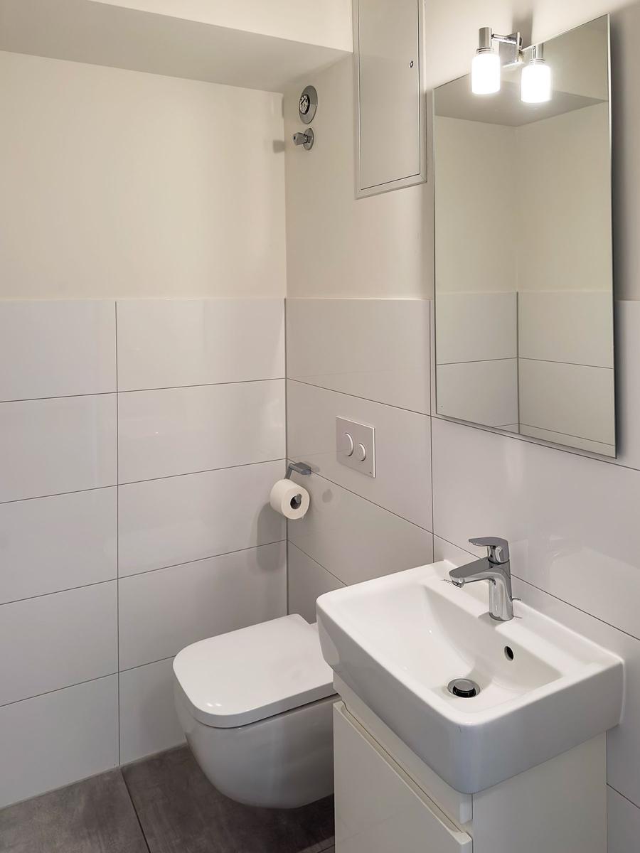 Badezimmer mit Toilette, Waschbecken und Spiegel.