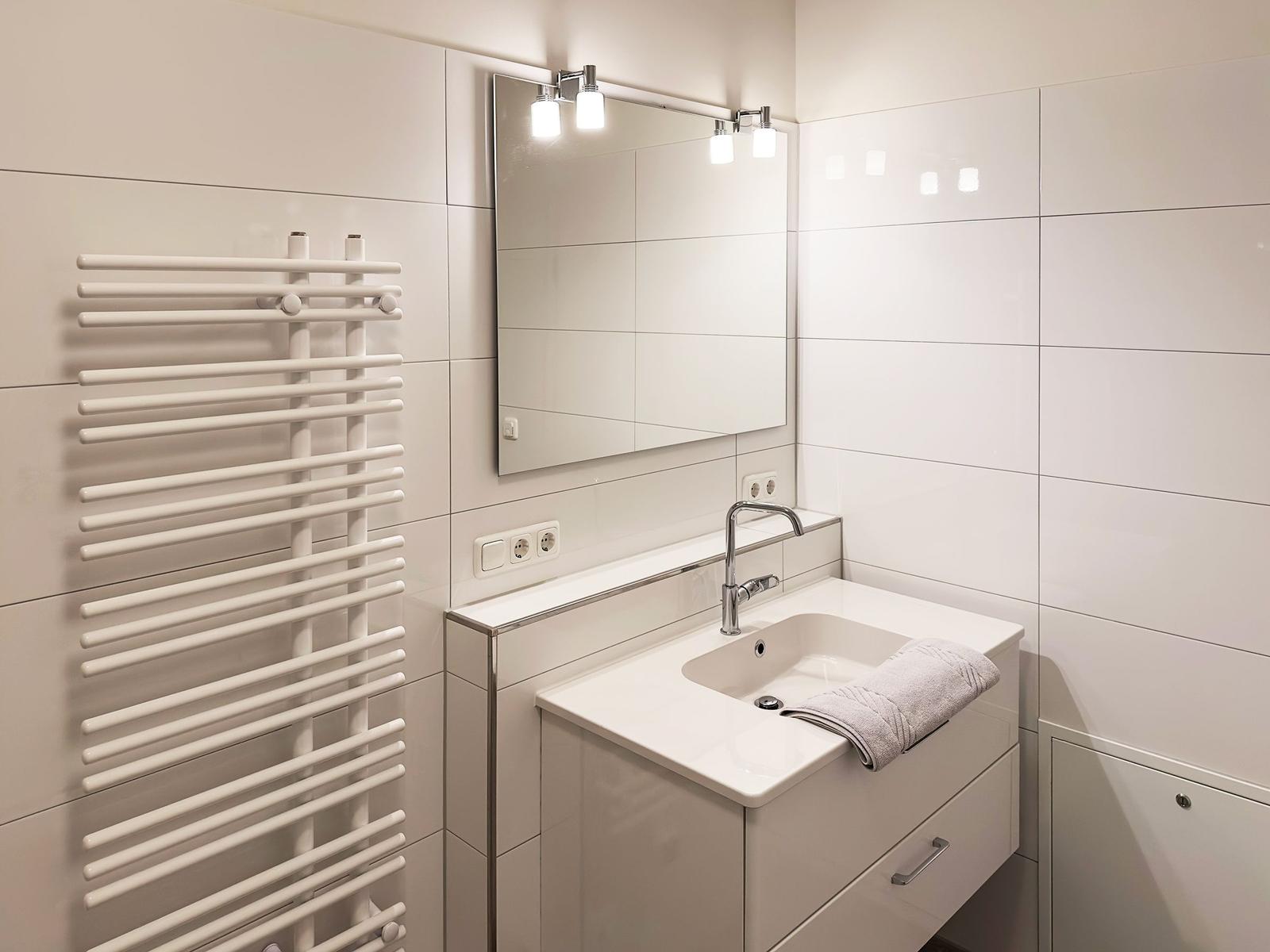 Badezimmer mit Waschbecken, Spiegel und Heizkörper