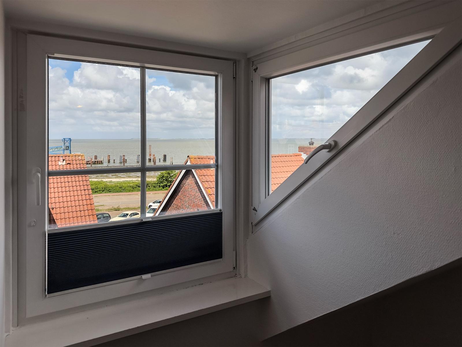 Zwei Fenster mit Blick auf Meer und Dächer