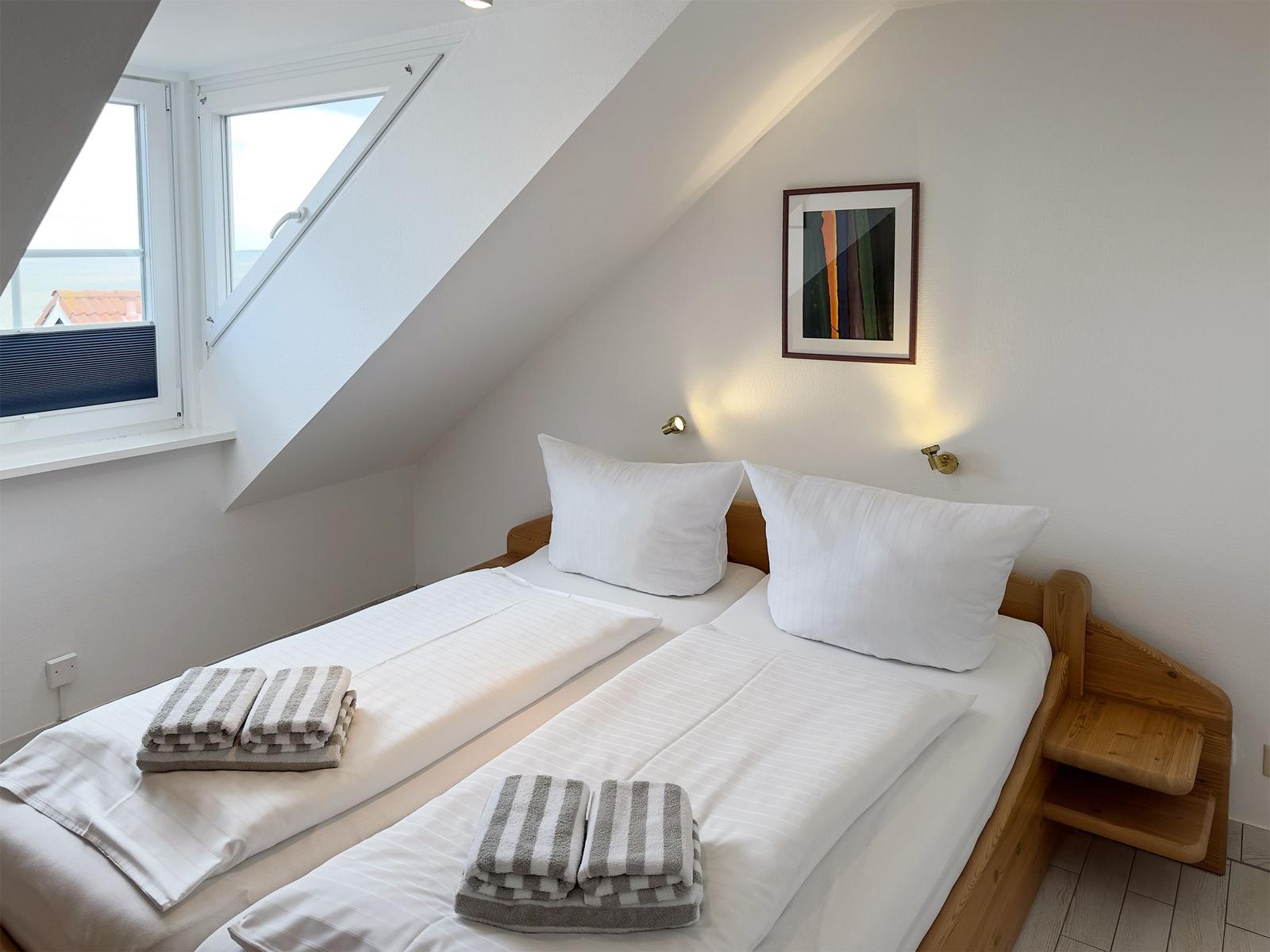 Zimmer mit Doppelbett, Fenster und Wandbild.