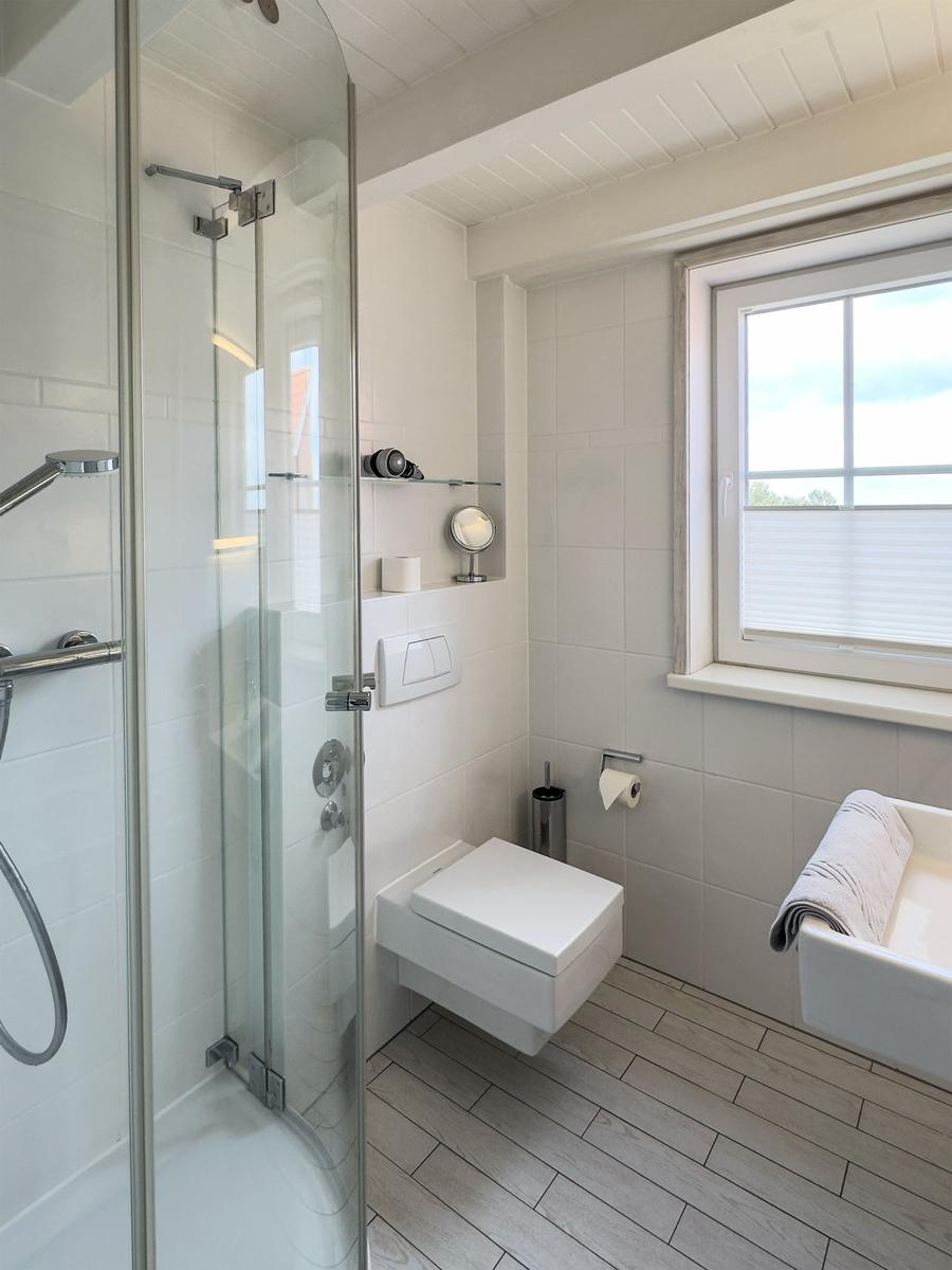 Bad mit Dusche, WC und Fenster mit Blick nach draußen.