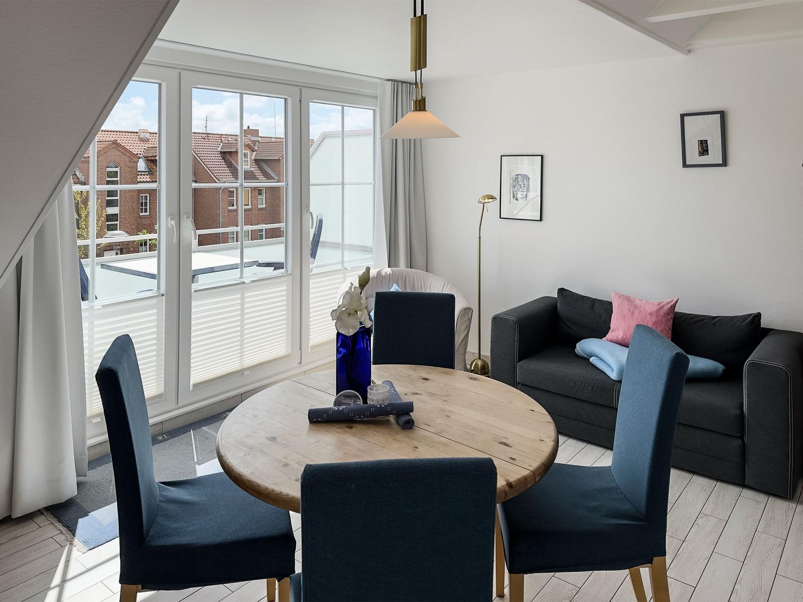 Rundtisch mit Stühlen, Sofa und Fenster zum Balkon.