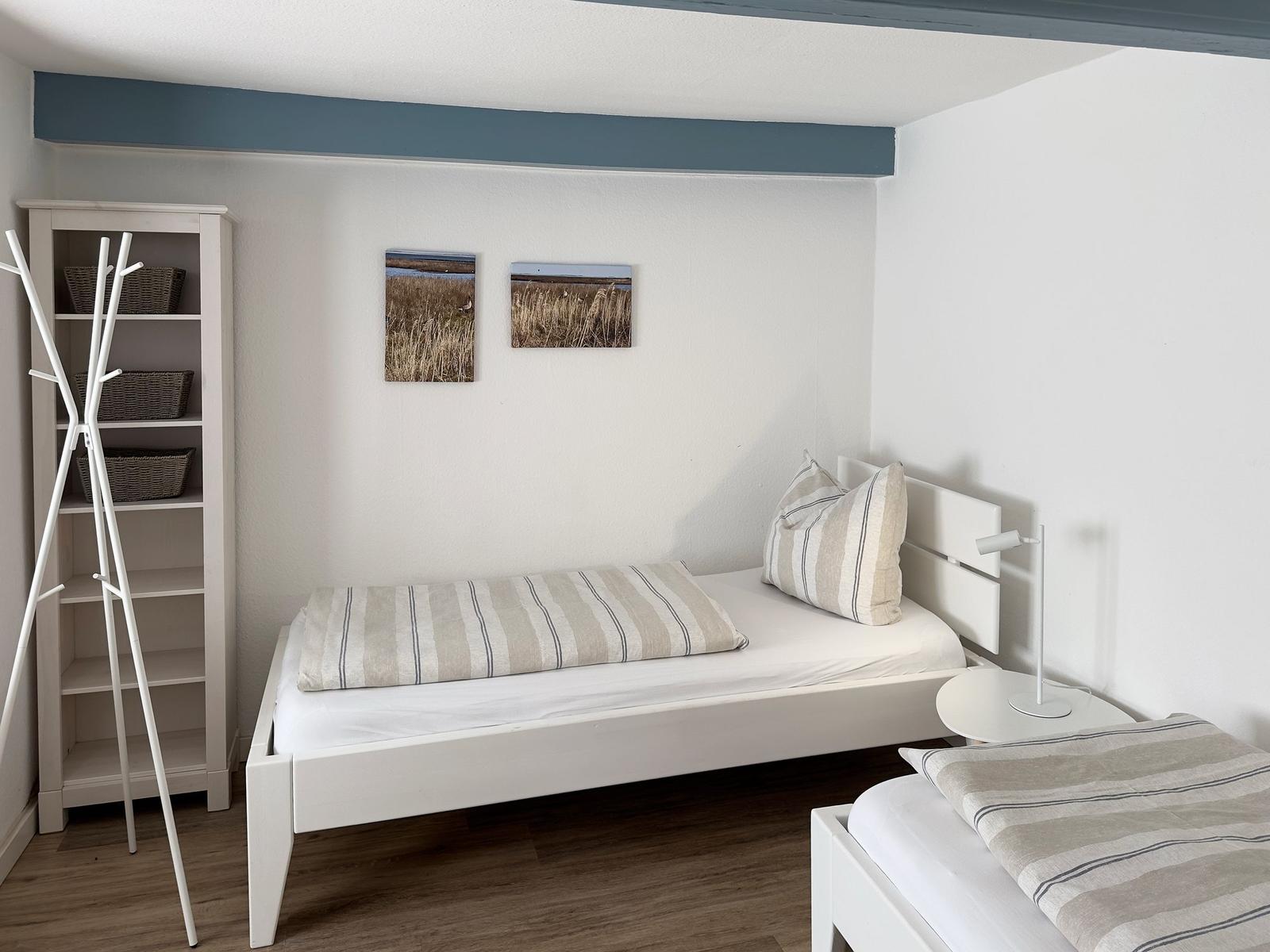 Zimmer mit zwei Betten, weißen Möbeln und Wandbildern
