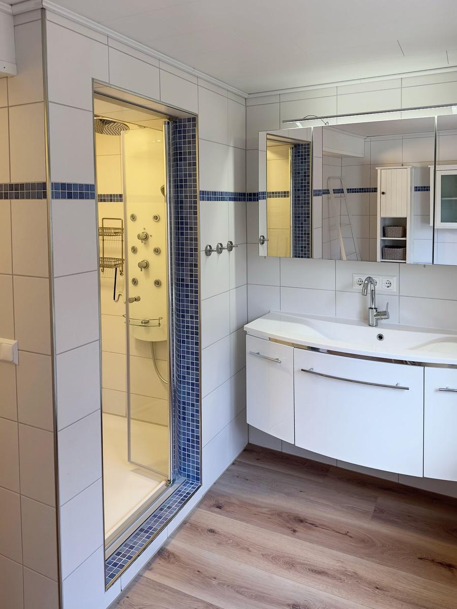 Badezimmer mit Dusche, Waschbecken und Spiegelschrank
