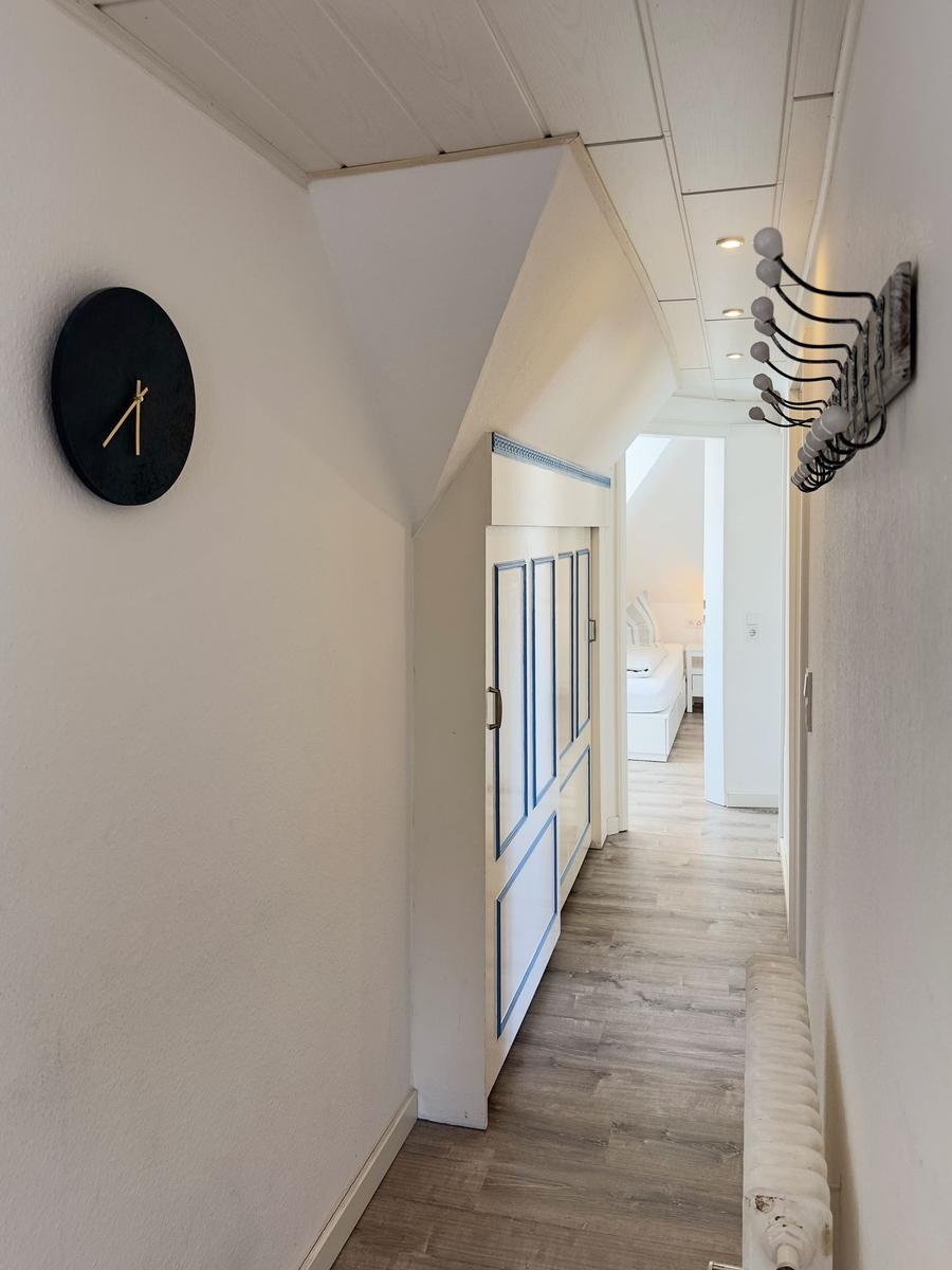 Flur mit Wanduhr, Garderobe und Blick in Schlafzimmer