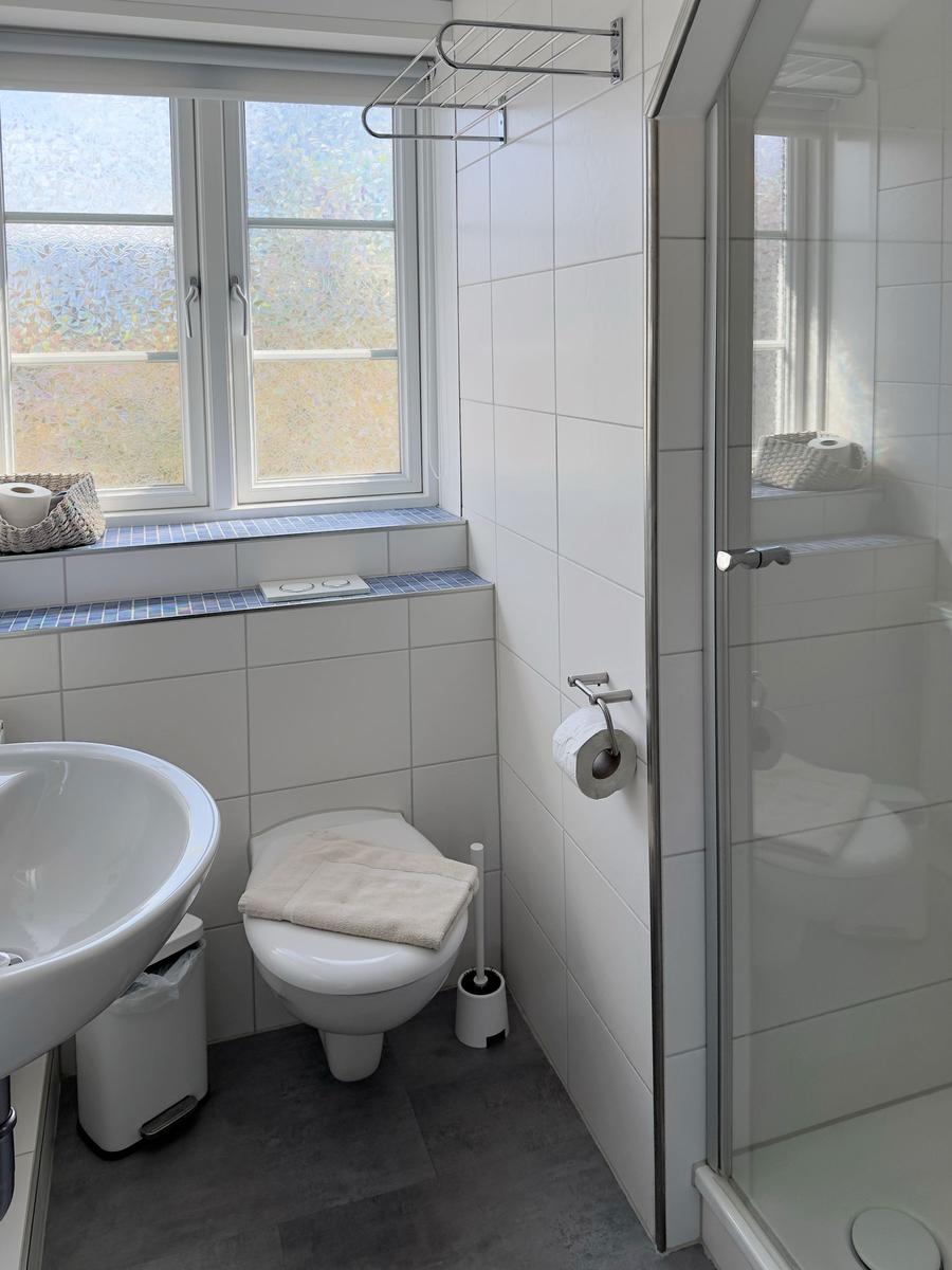 Bathroom with shower, toilet, and sink. Window with view.