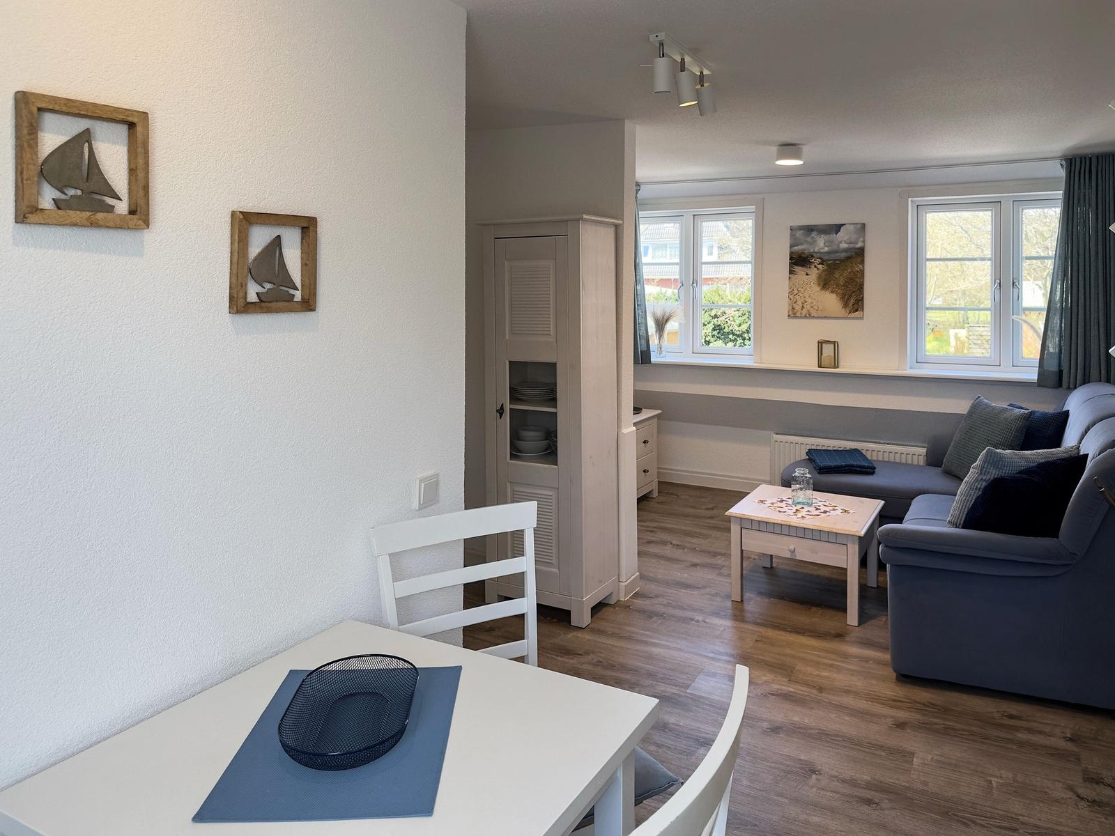 Living and dining area with sofa, table, and wall decor.