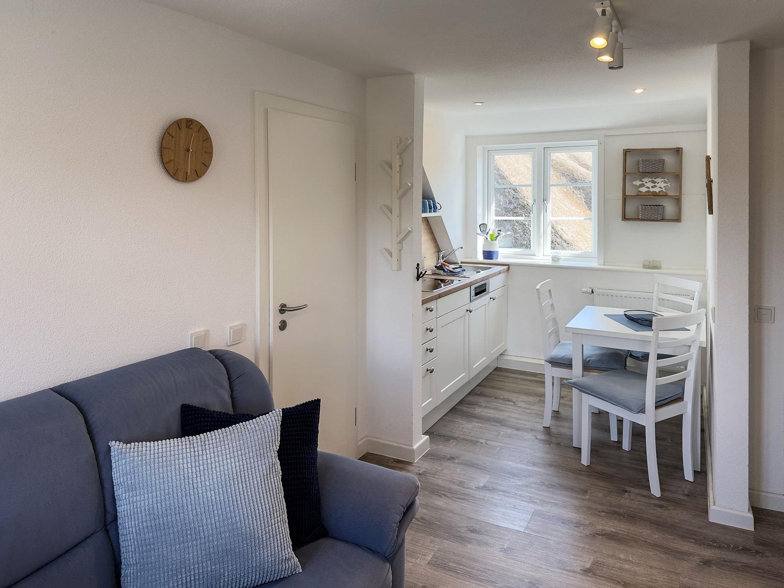 Living and dining area with kitchen, sofa, and table with chairs.