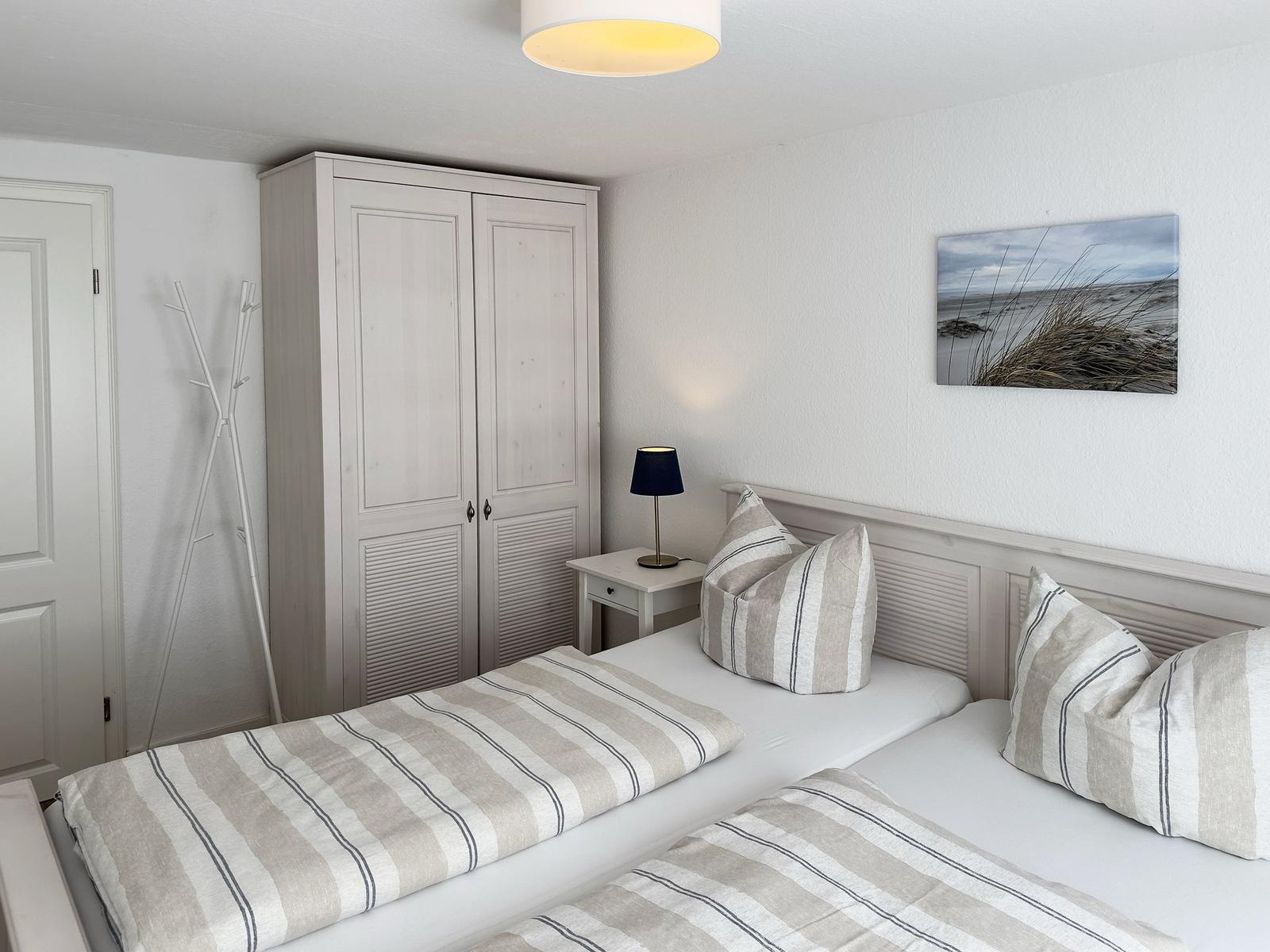 Zimmer mit zwei Betten, Kleiderschrank und Wandbild