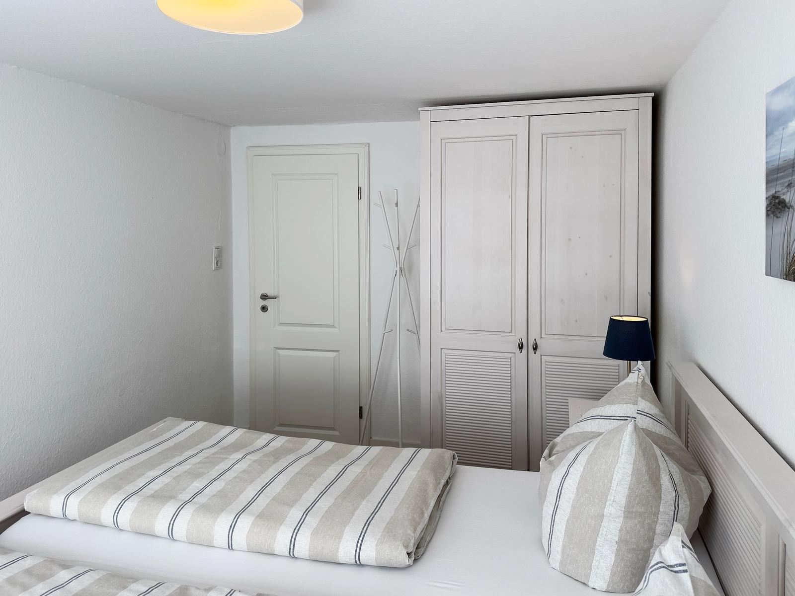 Schlafzimmer mit Bett, KleiderSchrank und Tür.
