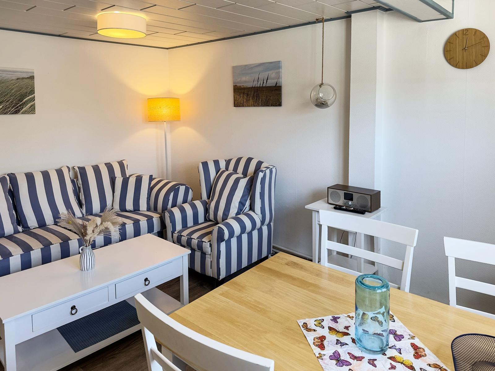 Wohn- und Essbereich mit gestreiftem Sofa, Tisch und Stühlen.