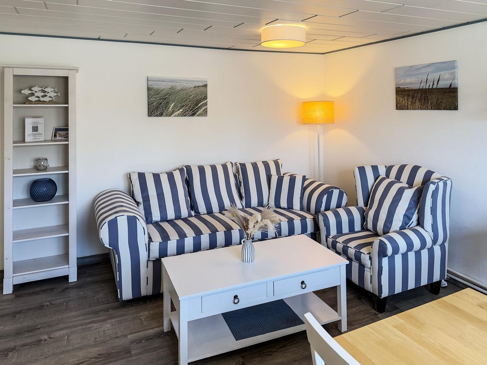 Wohnzimmer mit gestreiftem Sofa, Beistelltisch und Wandbildern