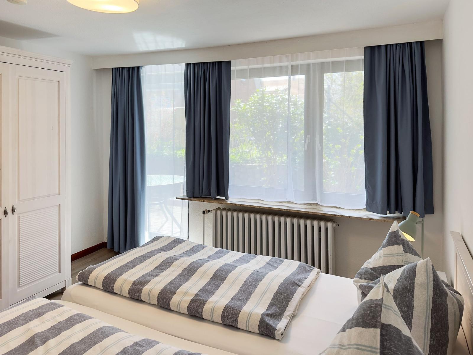 Bedroom with double bed, window, and curtains.
