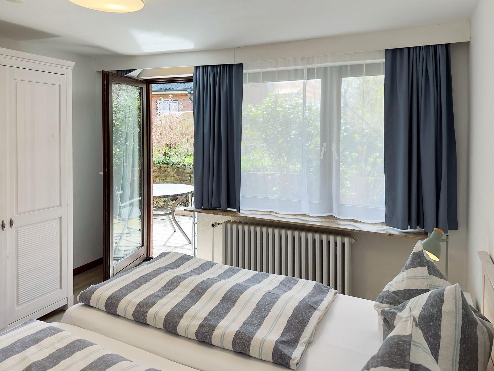 Room with bed, window, and door to garden. Curtain and radiator visible.