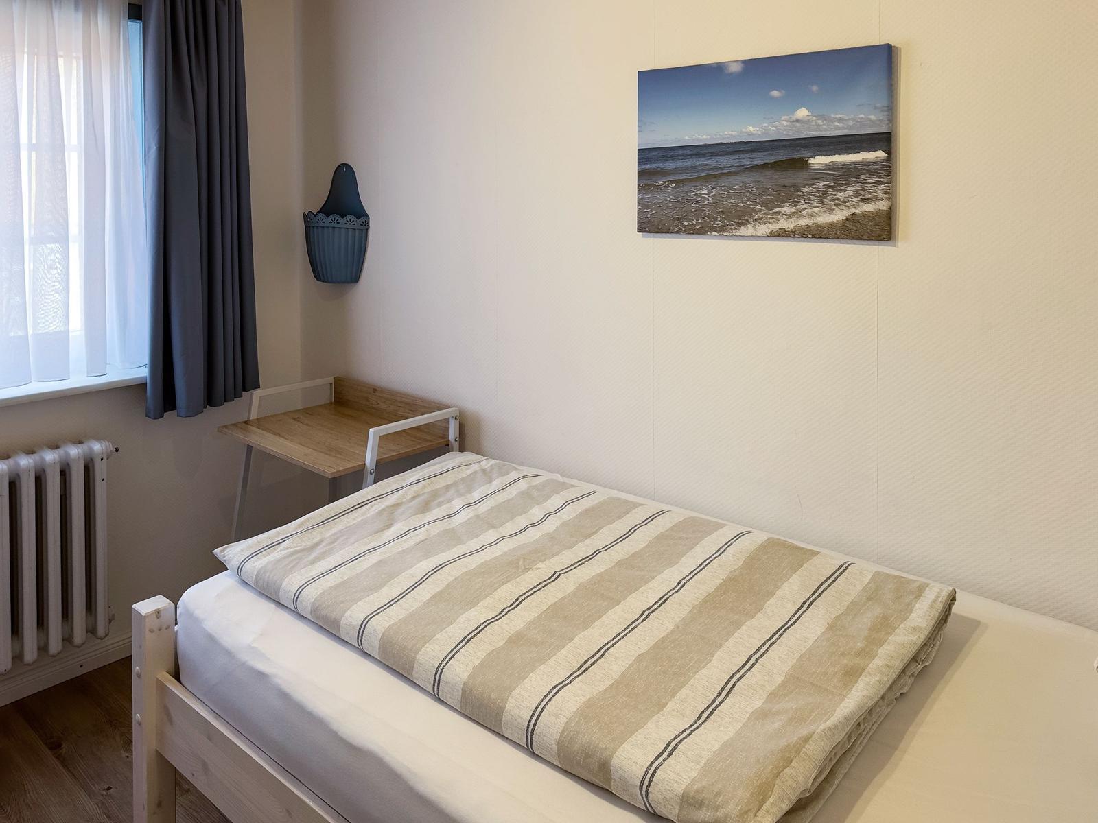 Bedroom with bed, desk, and wall picture