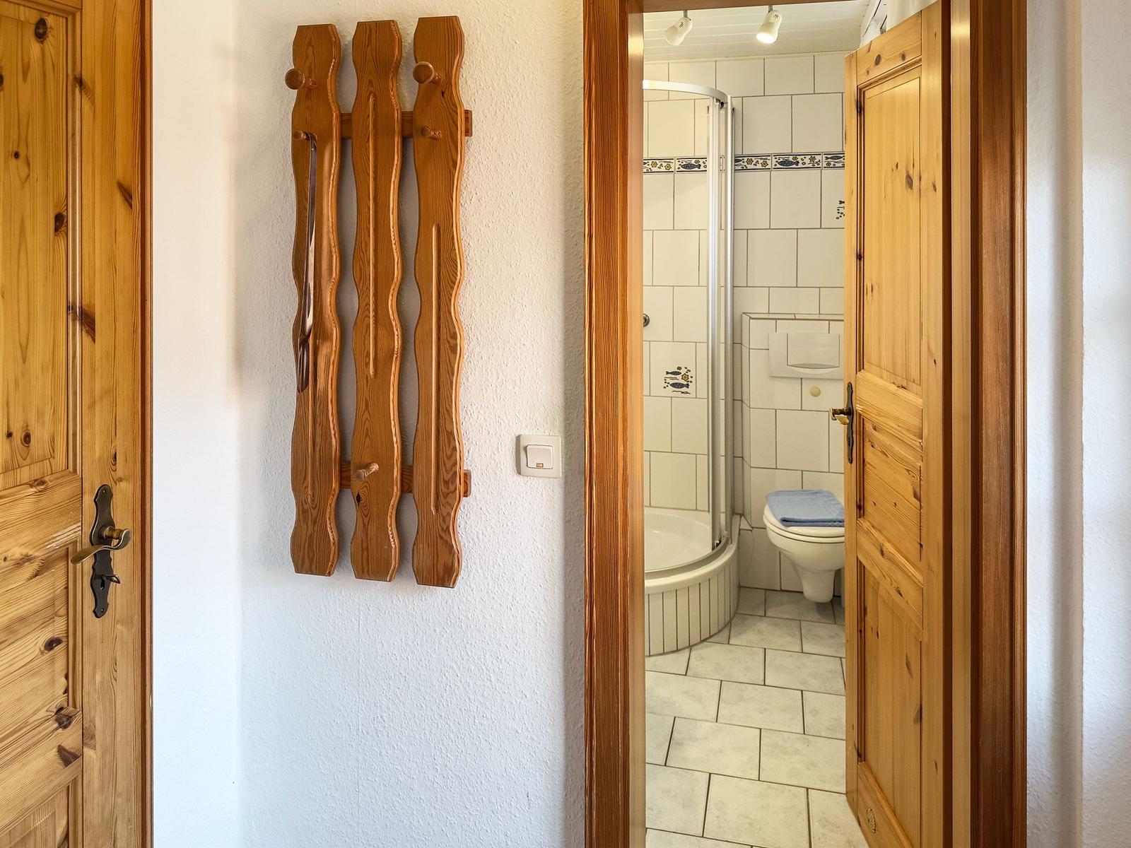 Bathroom with shower and toilet, wooden decor on the wall