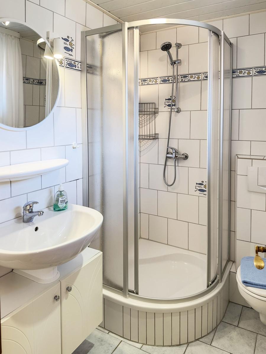 Bathroom with shower, sink and toilet. Tiles with fish motif.