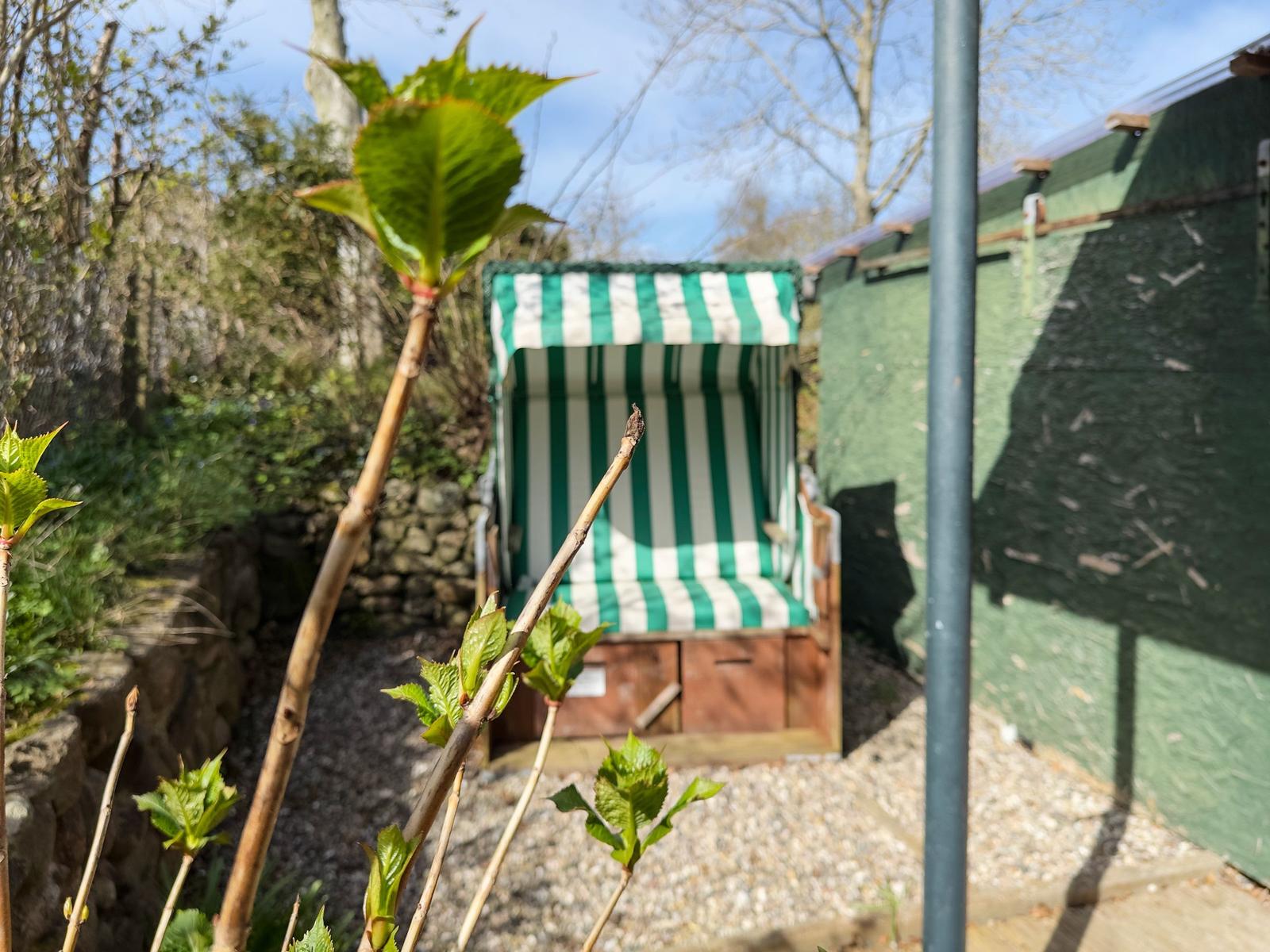 Green beach chair with striped pattern in garden area.