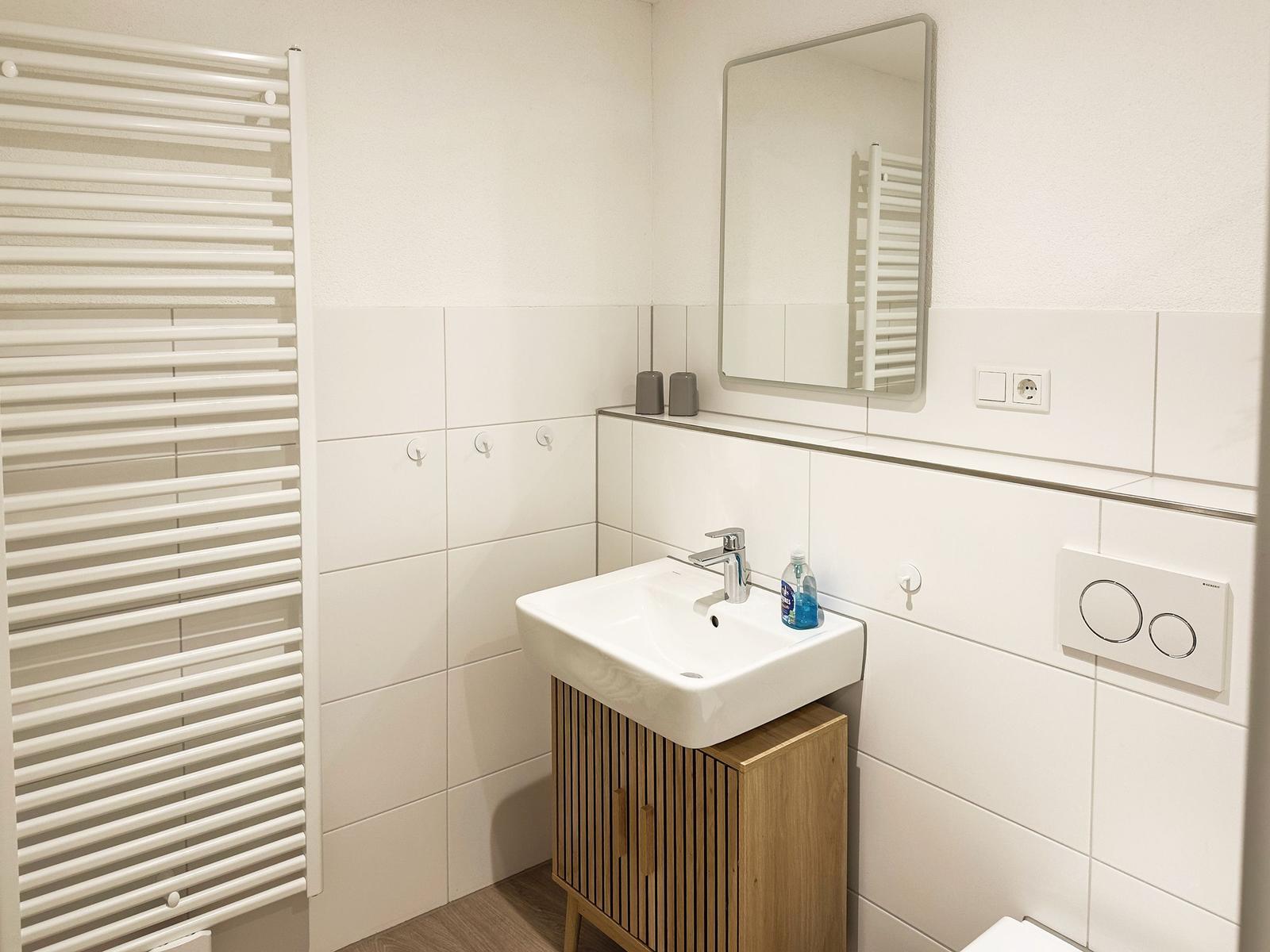 Badezimmer mit Waschbecken, Spiegel und Heizkörper
