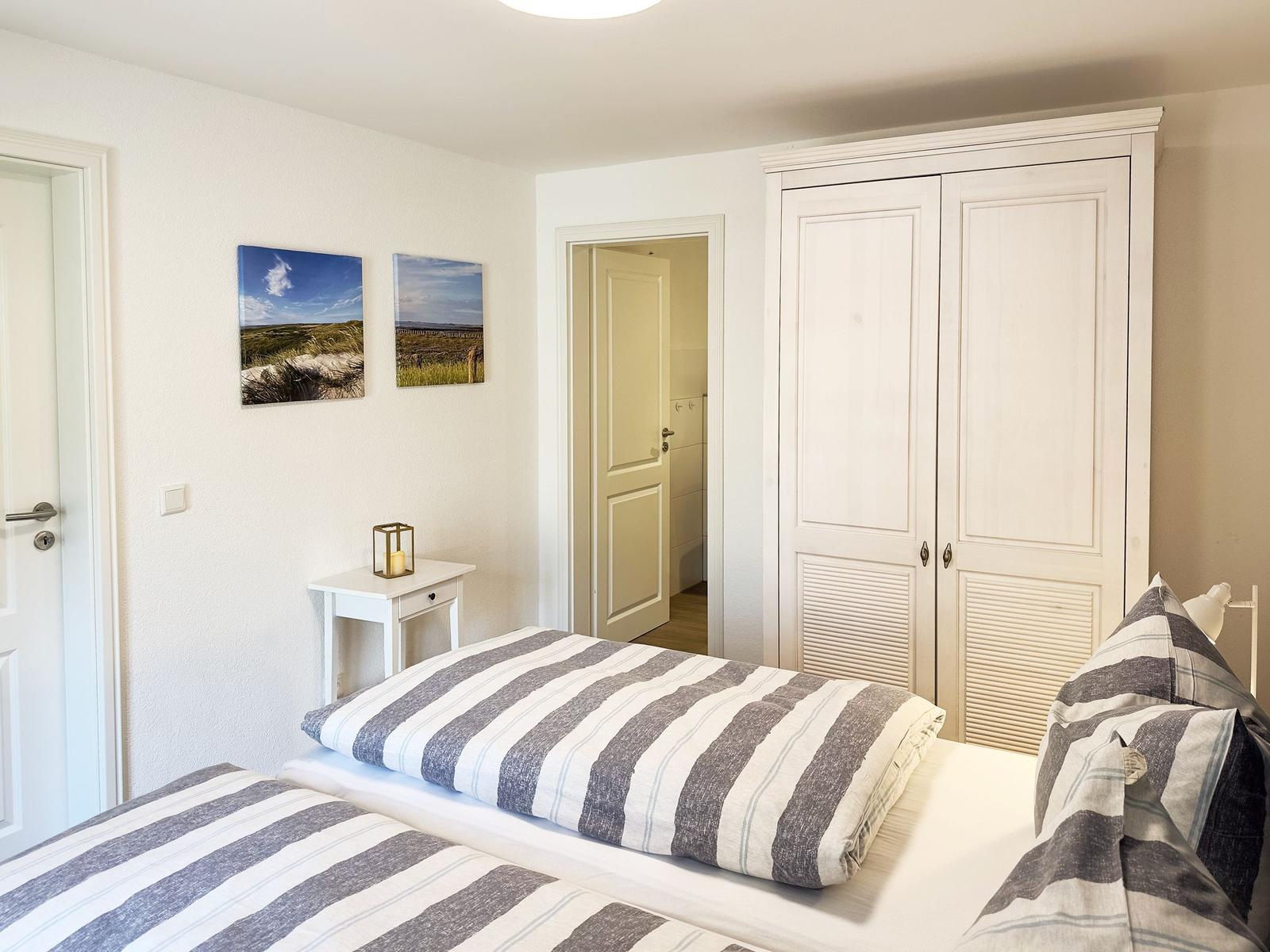 Schlafzimmer mit Doppelbett, Kleiderschrank und Wandbildern
